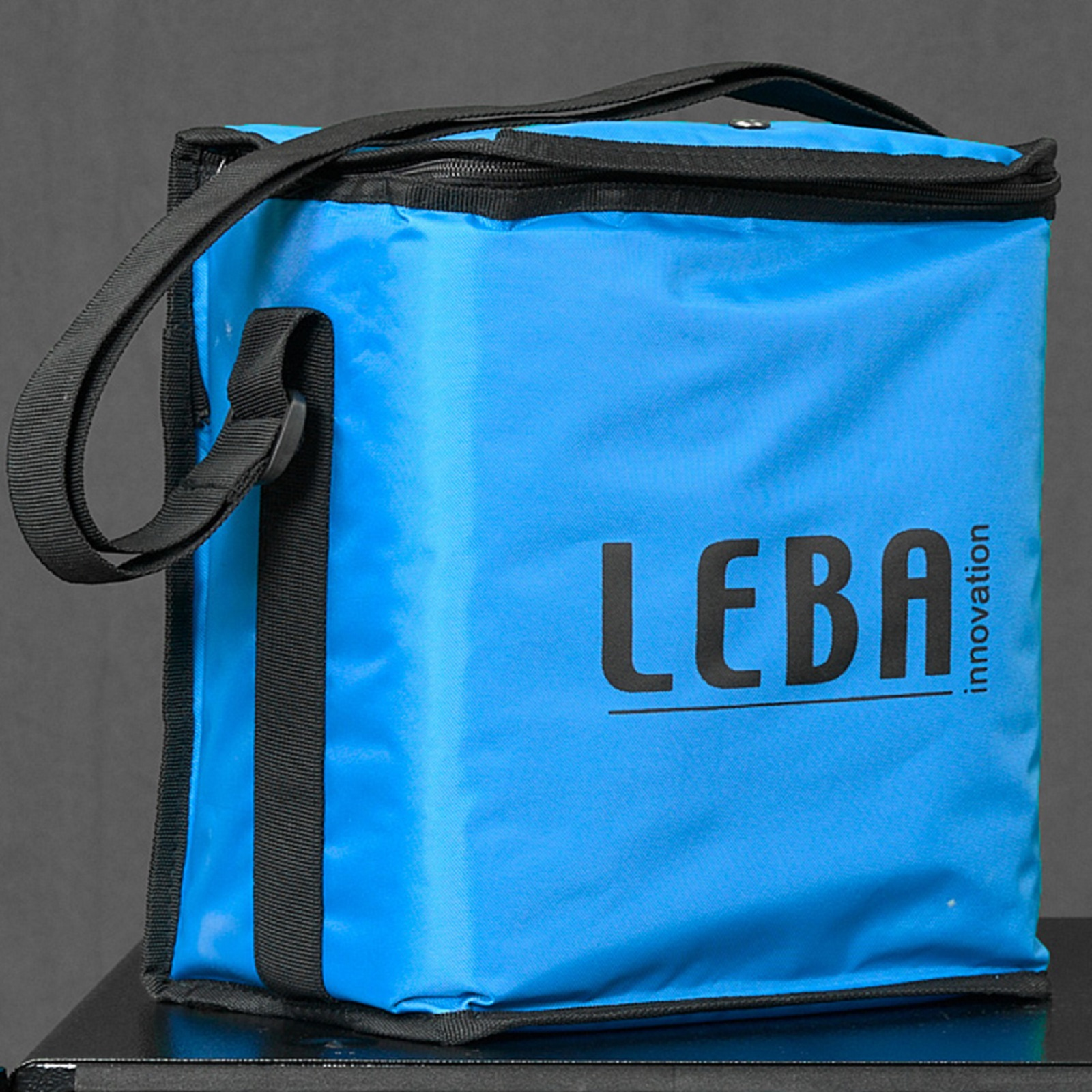Blaue Kühltasche mit schwarzem Besatz und Griff, mit dem Wort 'LEBA' vorne.