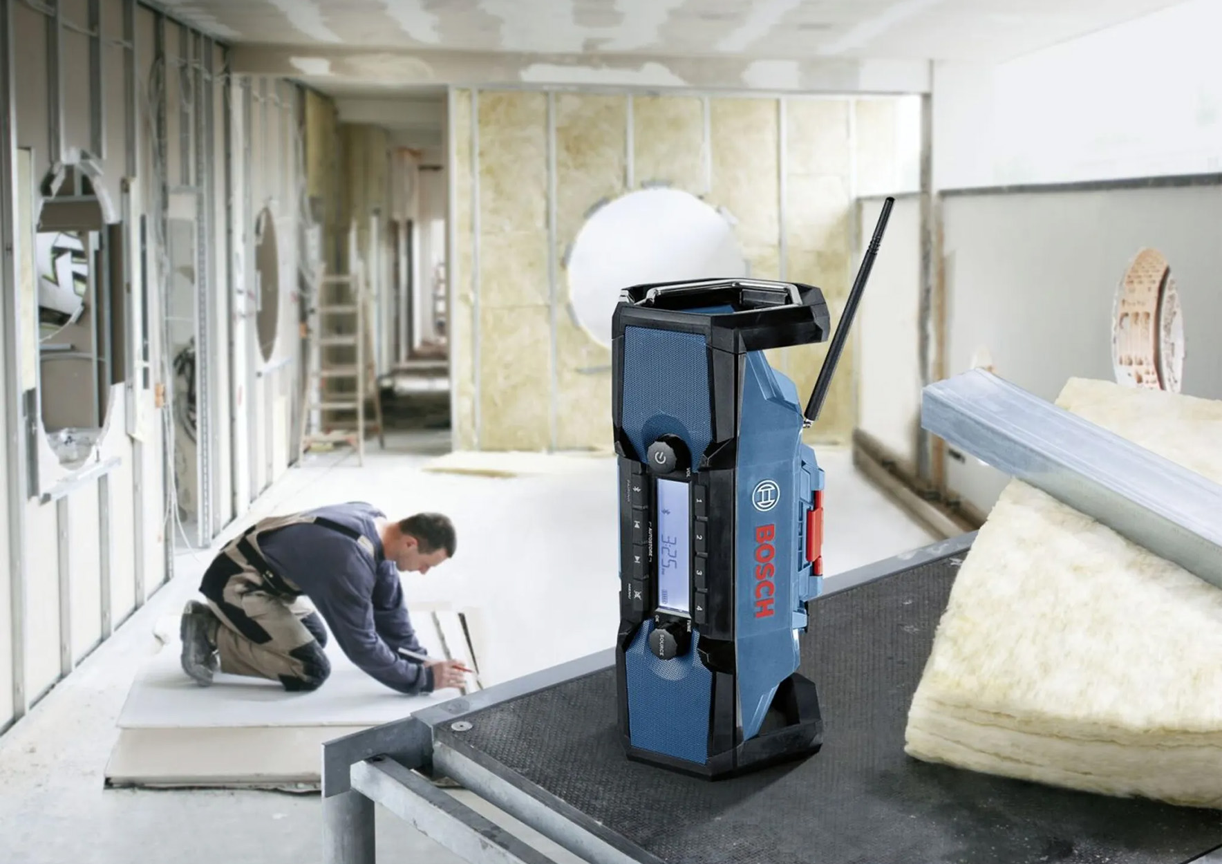 Robotnik budowlany używający radia na budowie z izolacją.