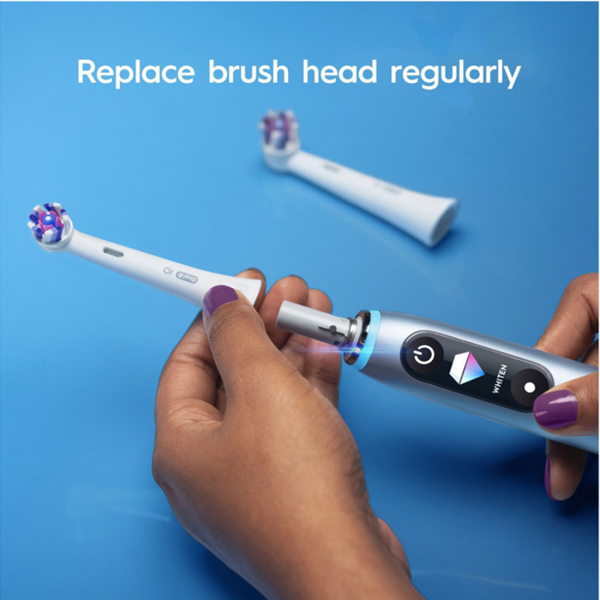 Osoba trzymająca główkę szczoteczki do zębów i szczoteczkę elektryczną. Niebieskie tło.