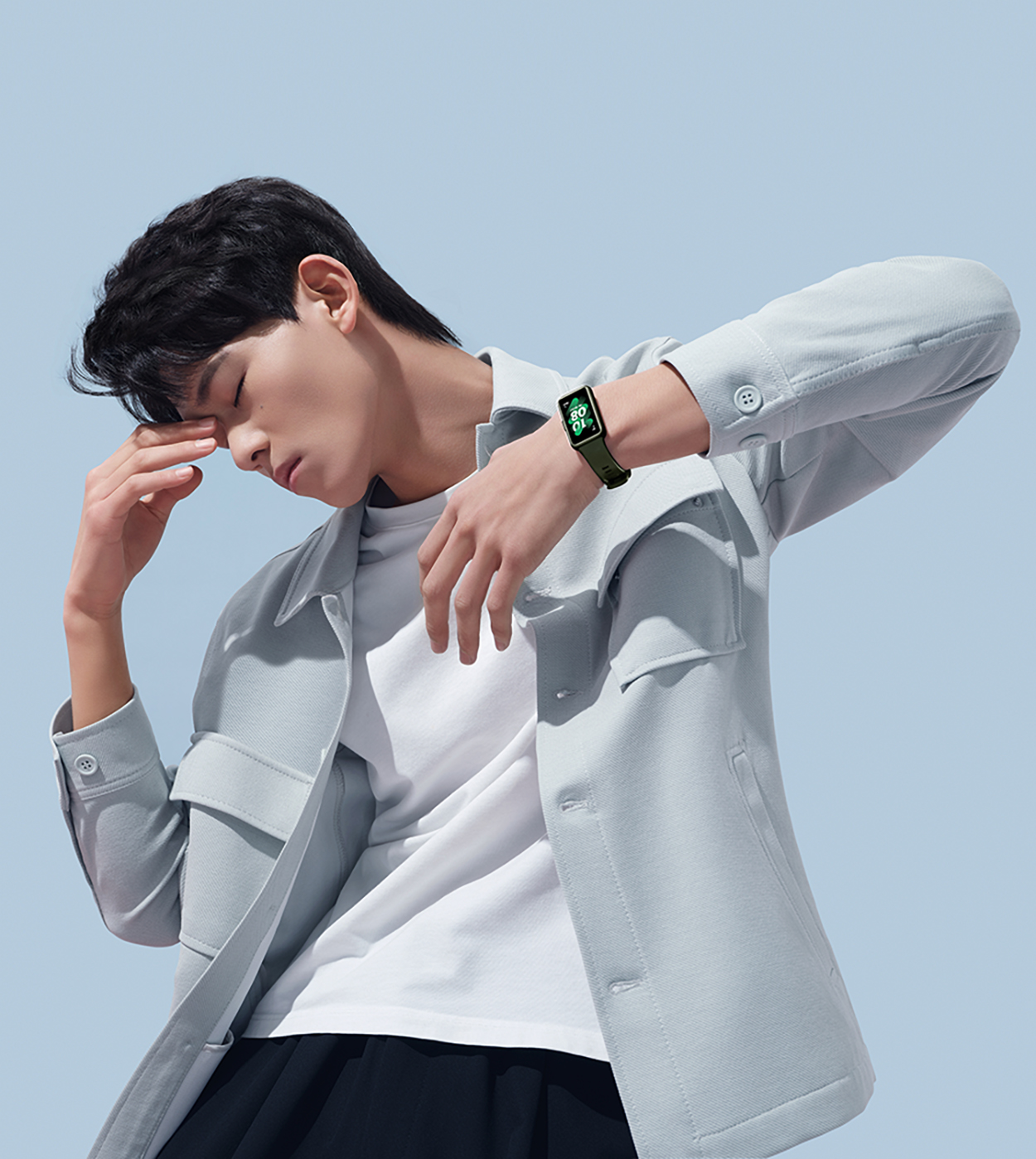 Uomo con orologio, braccio alzato. L'orologio è verde. Lo sfondo è azzurro.