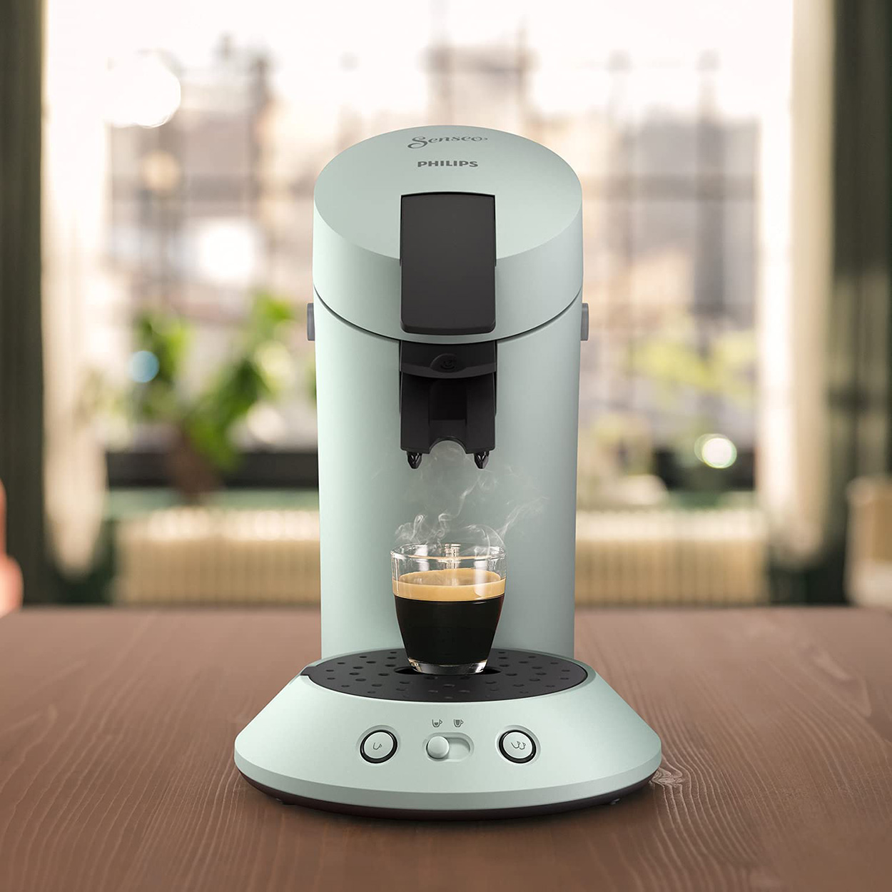 Eine hellgrüne Philips Senseo Kaffeemaschine mit einer Tasse Kaffee.