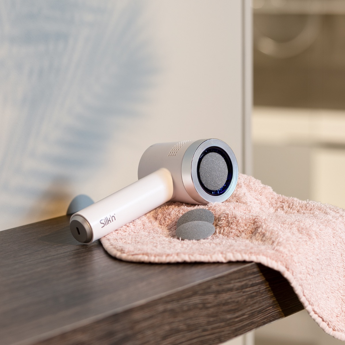 Białe i szare urządzenie do pielęgnacji stóp z różowym ręcznikiem i szarymi wkładkami.