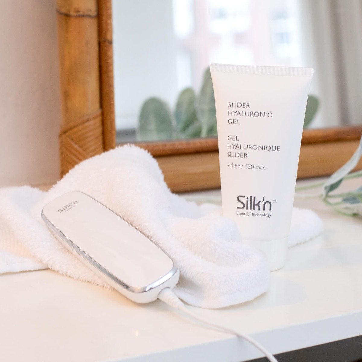 Hautpflegeprodukte auf einem Tisch: Geltube, weißes Handtuch und ein Gerät.