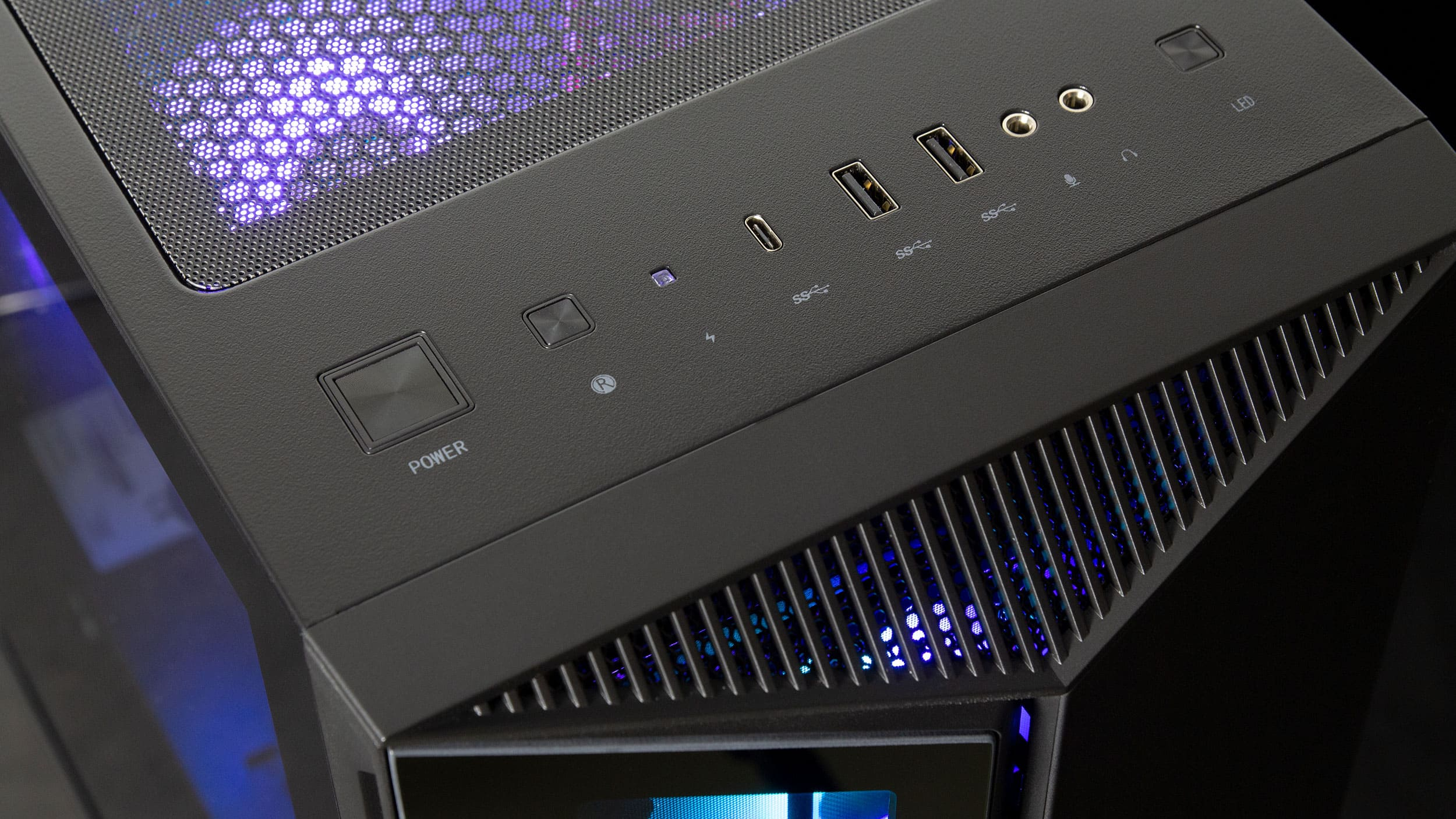 Nahaufnahme eines schwarzen Computergehäuses mit blauen Lichtern und verschiedenen Anschlüssen oben.