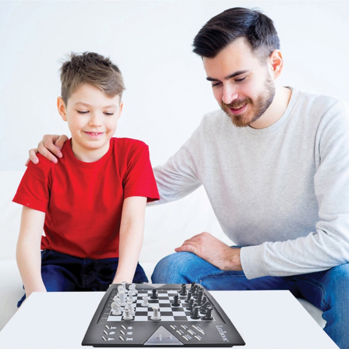 Niño y hombre jugando ajedrez. Niño mira el tablero. Hombre toca el hombro del niño.