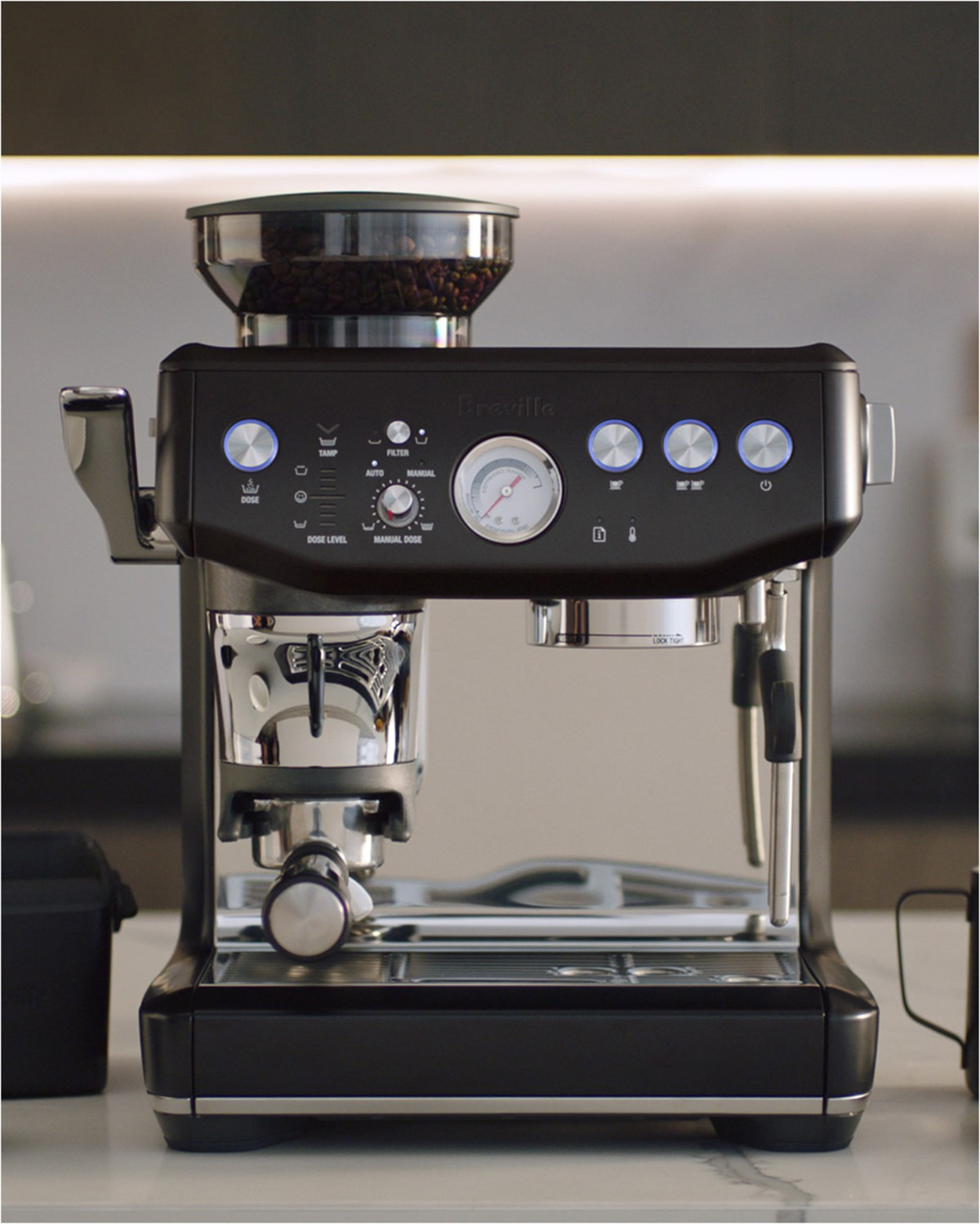 Czarny ekspres do kawy Breville z młynkiem do ziaren kawy, pokrętłem i przyciskami na białej powierzchni.