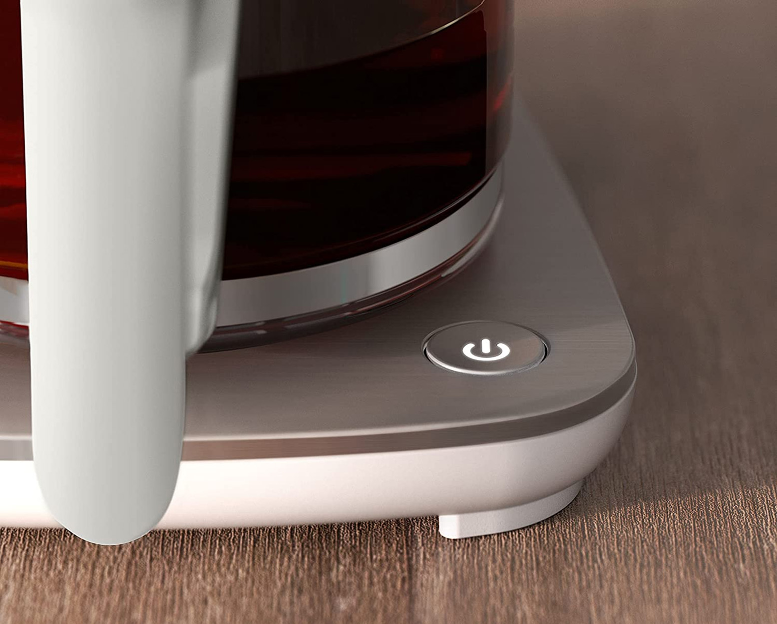 Zbliżenie białej i srebrnej podstawy czajnika z przyciskiem zasilania.