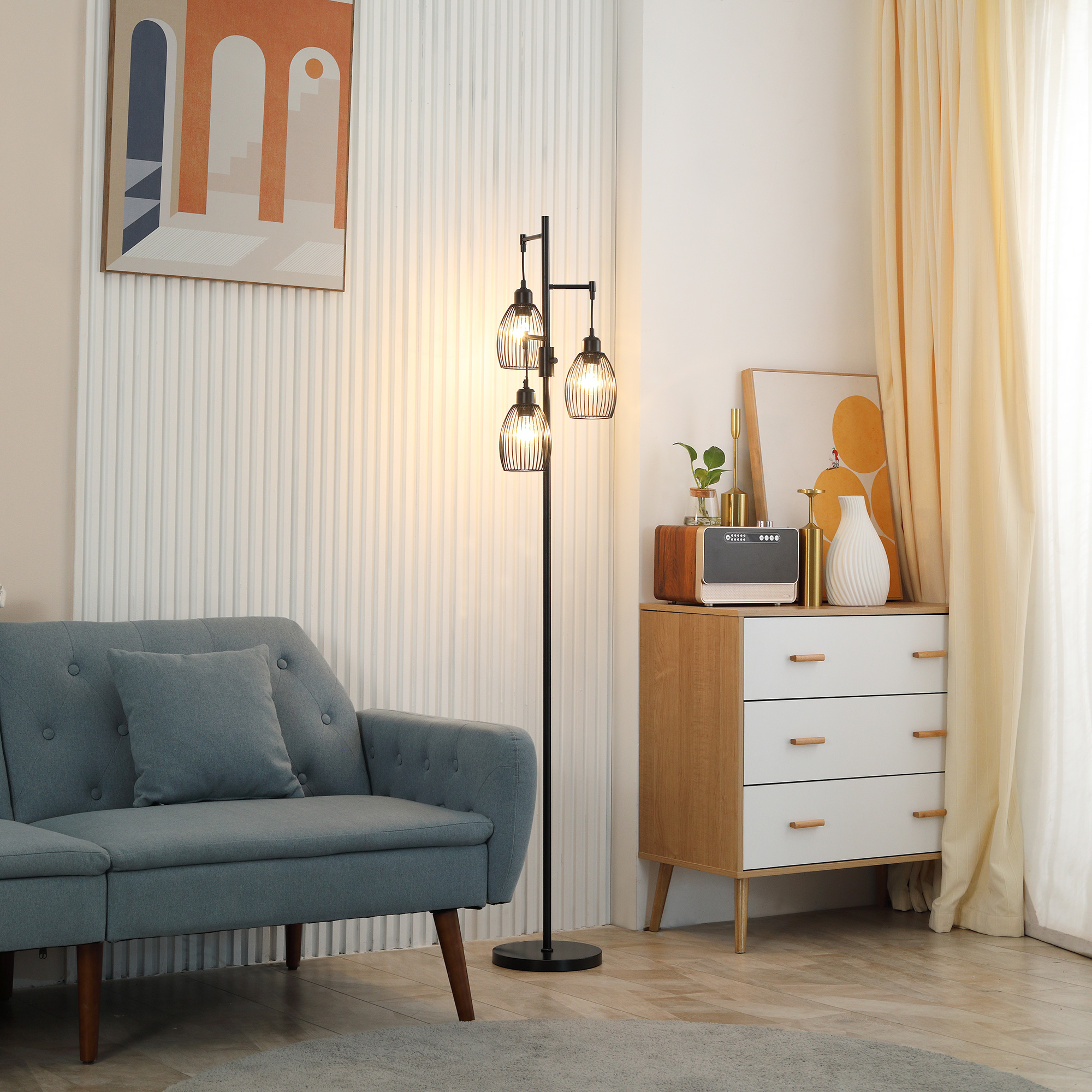 Un divano blu accanto a una lampada da terra a tre luci e un comò decorato.