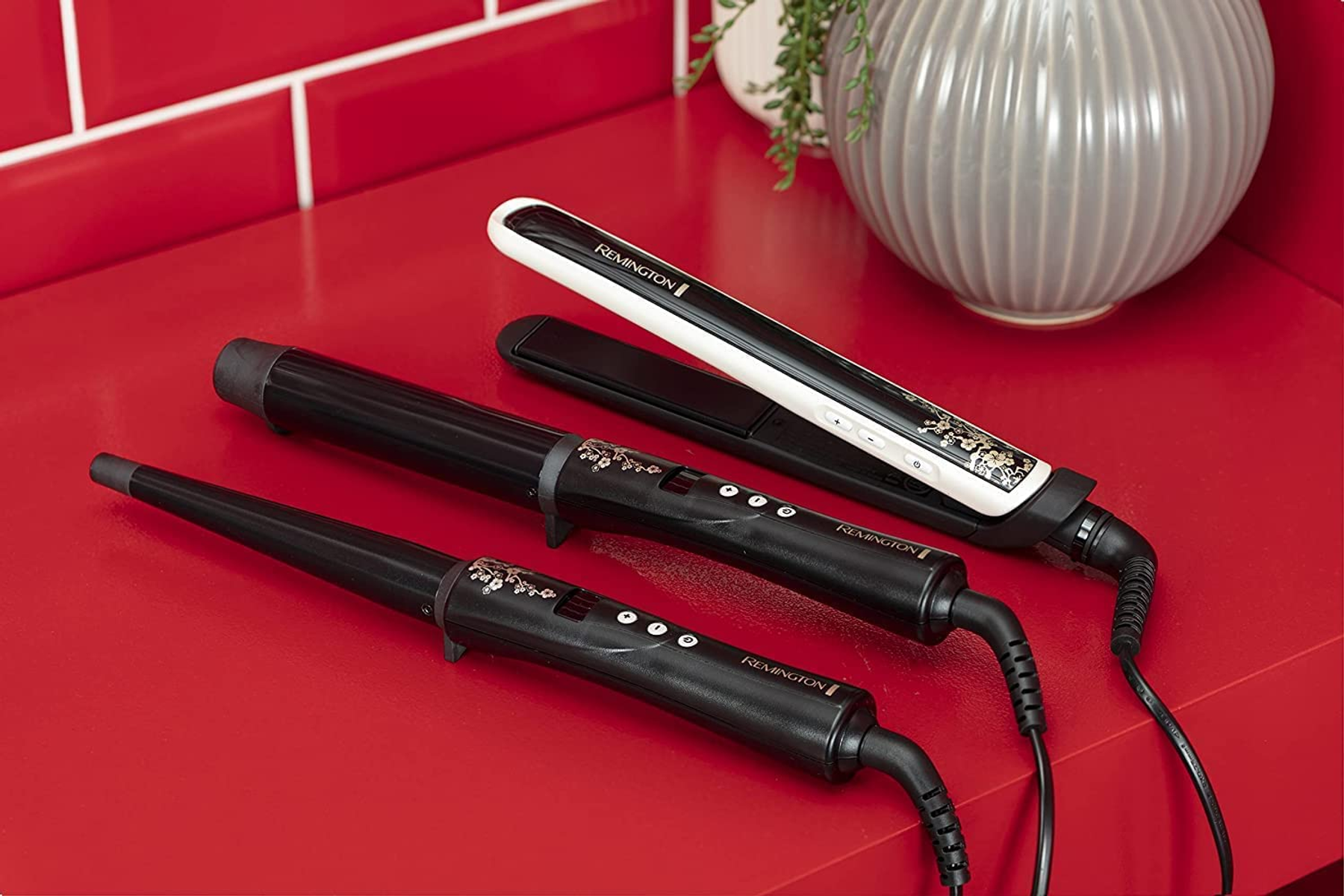Strumenti per lo styling dei capelli: arricciacapelli e piastra, su superficie rossa.