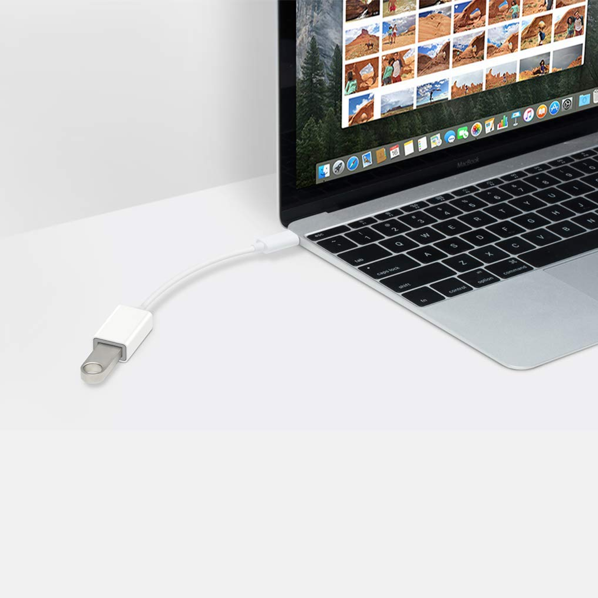 Ein Laptop ist mit einem USB-Adapter verbunden, der sich auf einer weißen Oberfläche befindet.