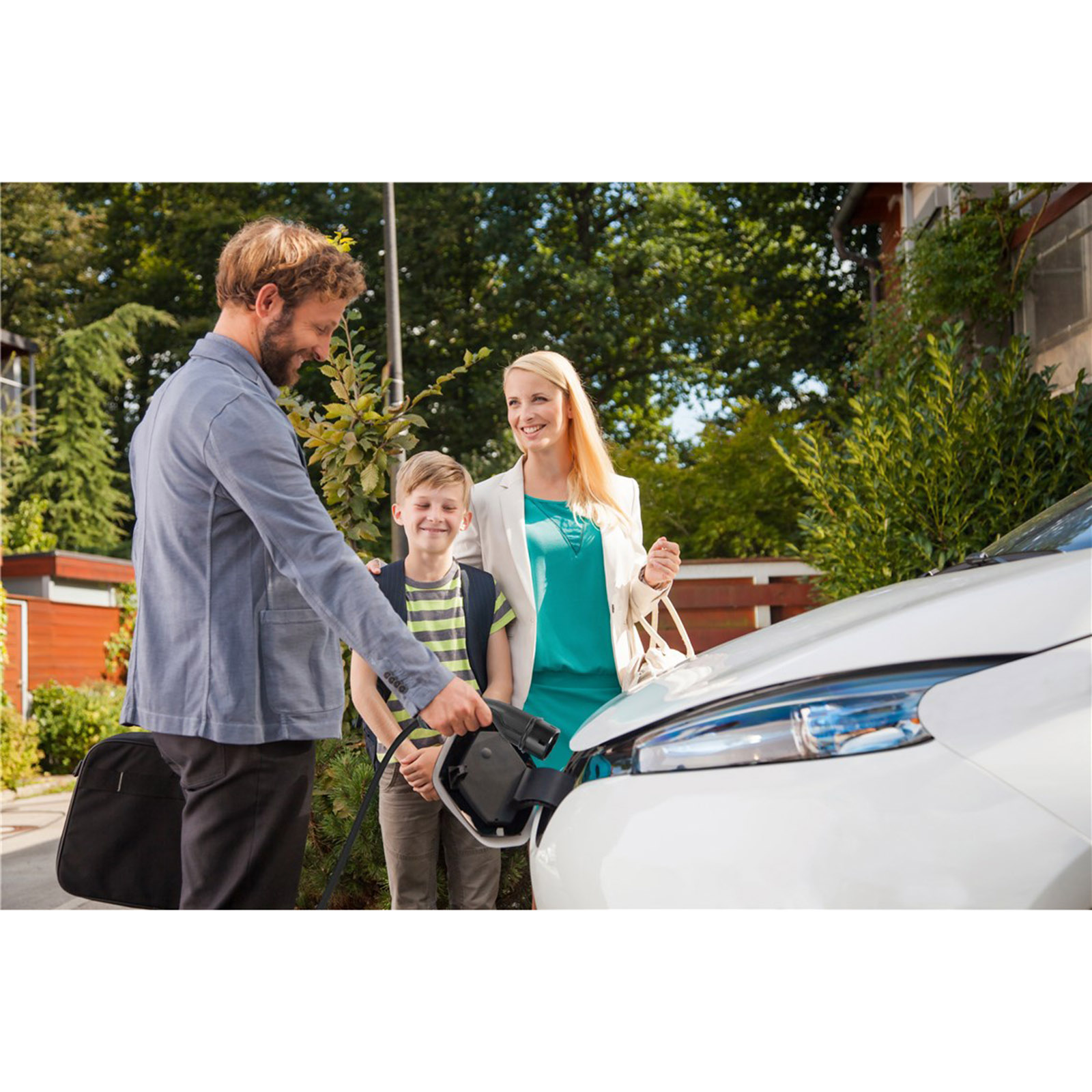 Eine Familie lädt ein Elektroauto auf, das Ladekabel ist angeschlossen.
