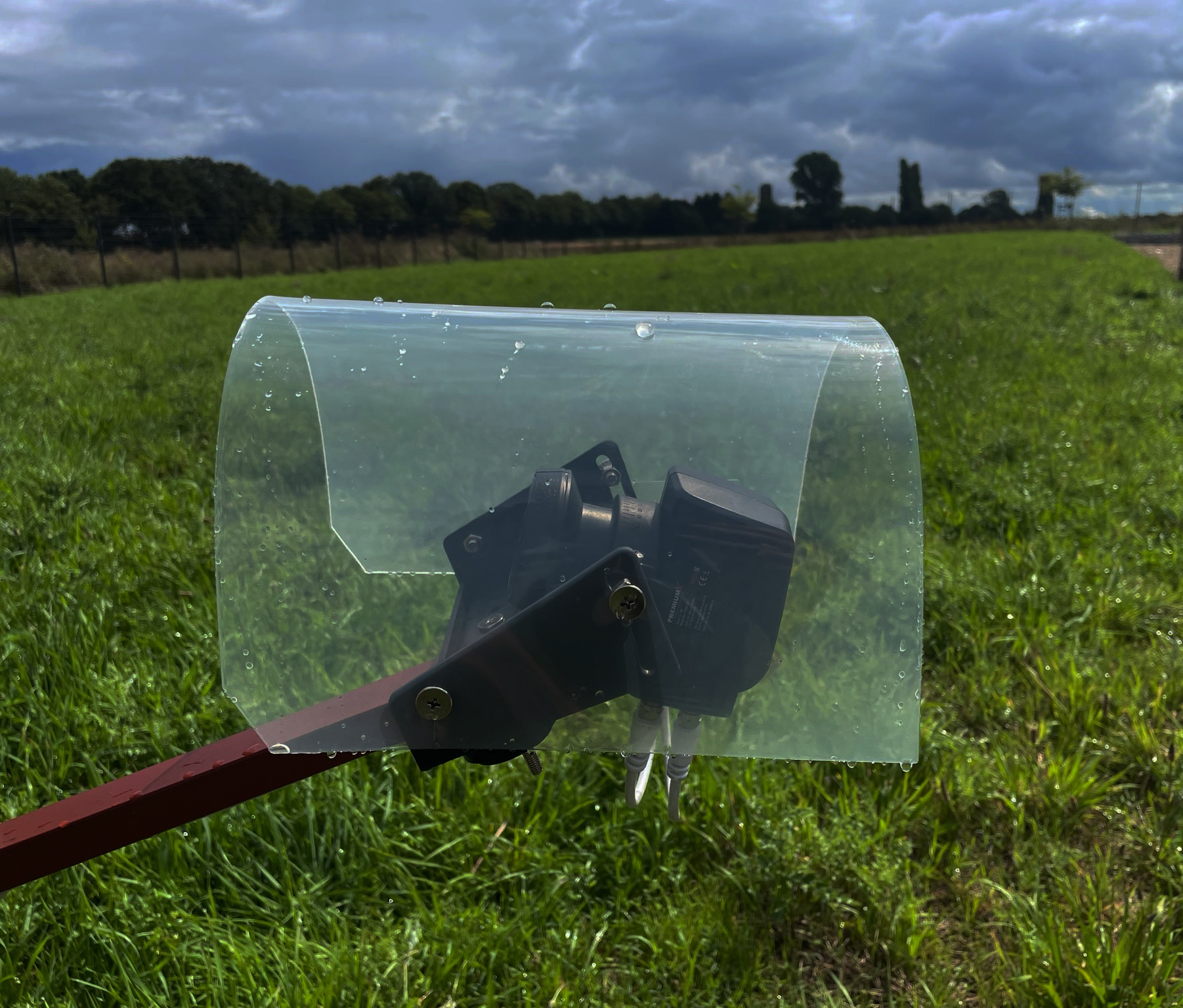 Landwirtschaftliches Gerät auf dem Feld. Klare Kunststoffabdeckung, bewölkter Himmel.