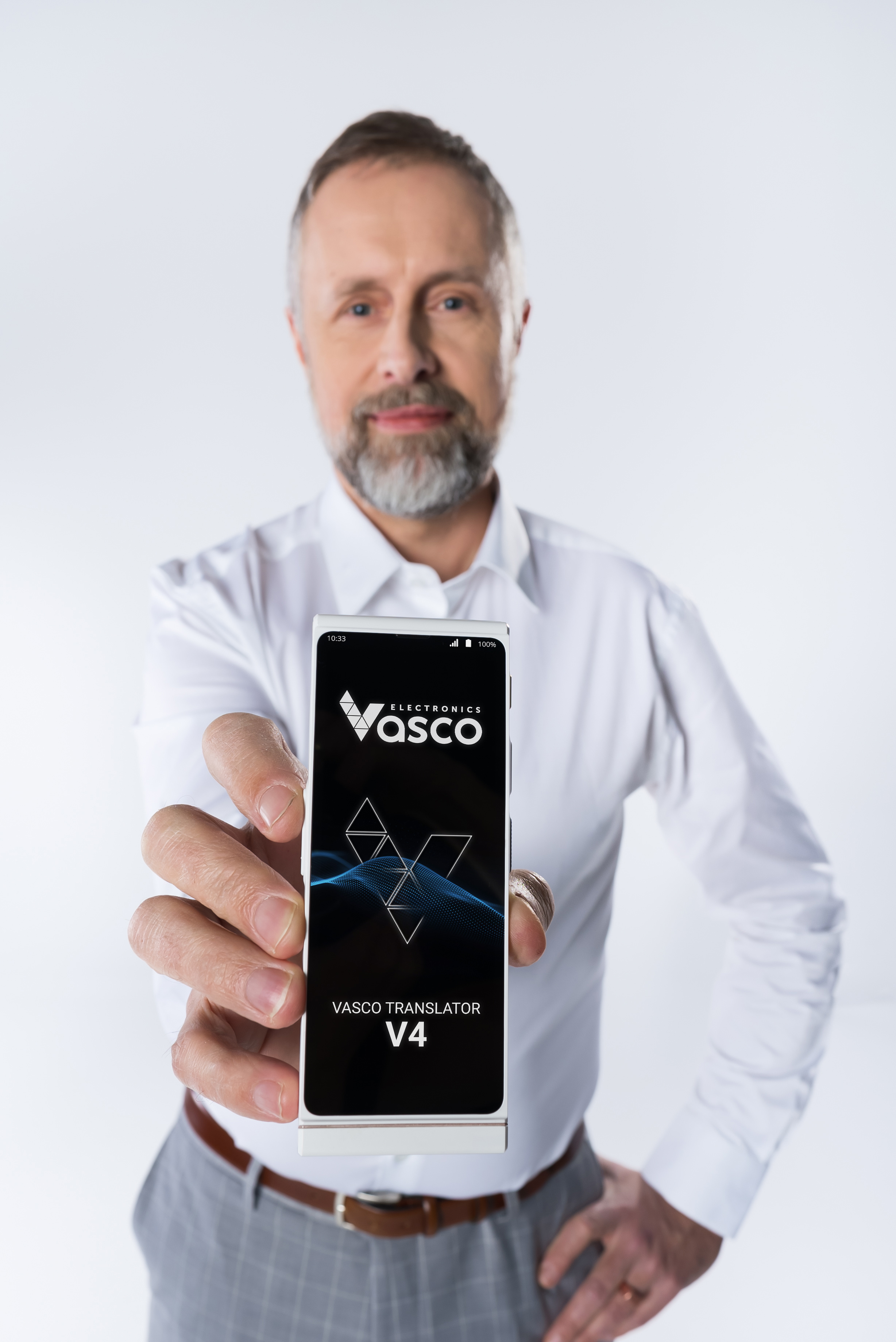 Mann hält Vasco Translator V4. Weißes Gerät mit Bildschirm und Logo vorne. Weißer Hintergrund.