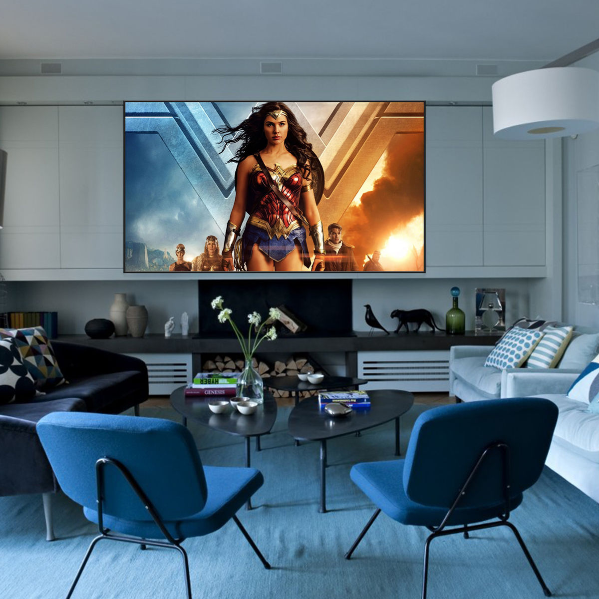 Salon avec un grand écran diffusant le film Wonder Woman. Deux chaises bleues font face à l'écran. Décor moderne.
