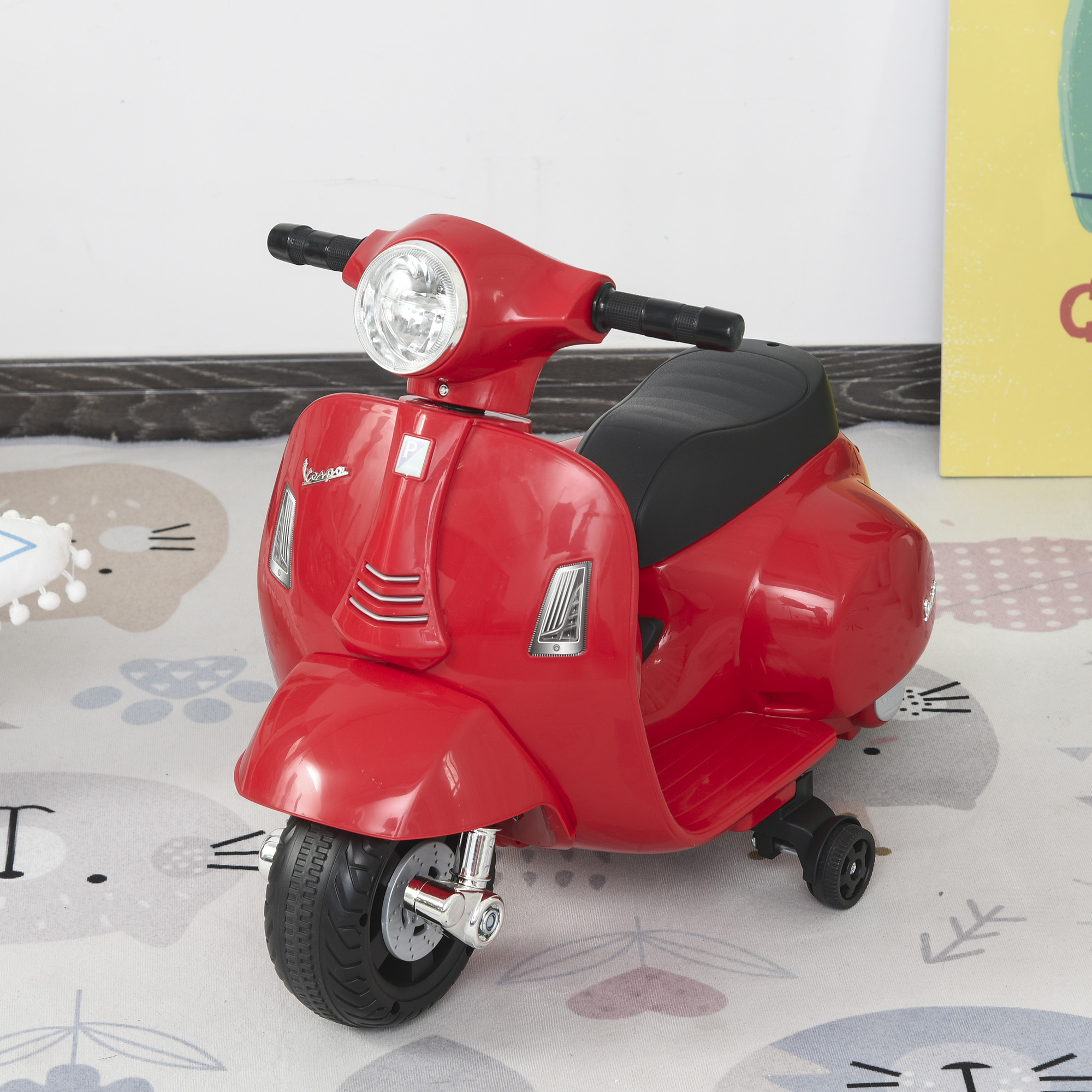 Uno scooter Vespa giocattolo rosso su un tappeto fantasia.