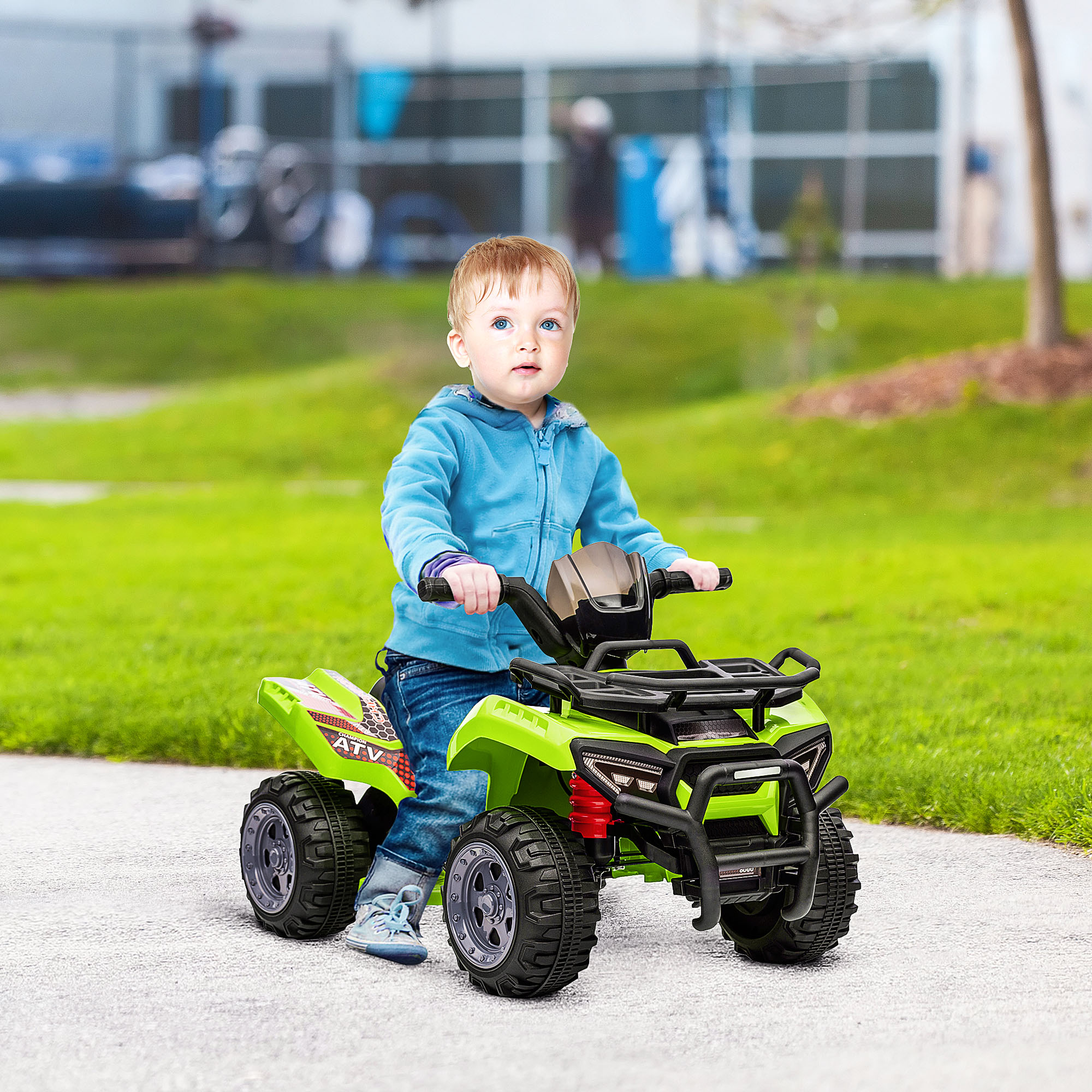 Bambino su un ATV verde su un sentiero lastricato, di fronte a erba e alberi.