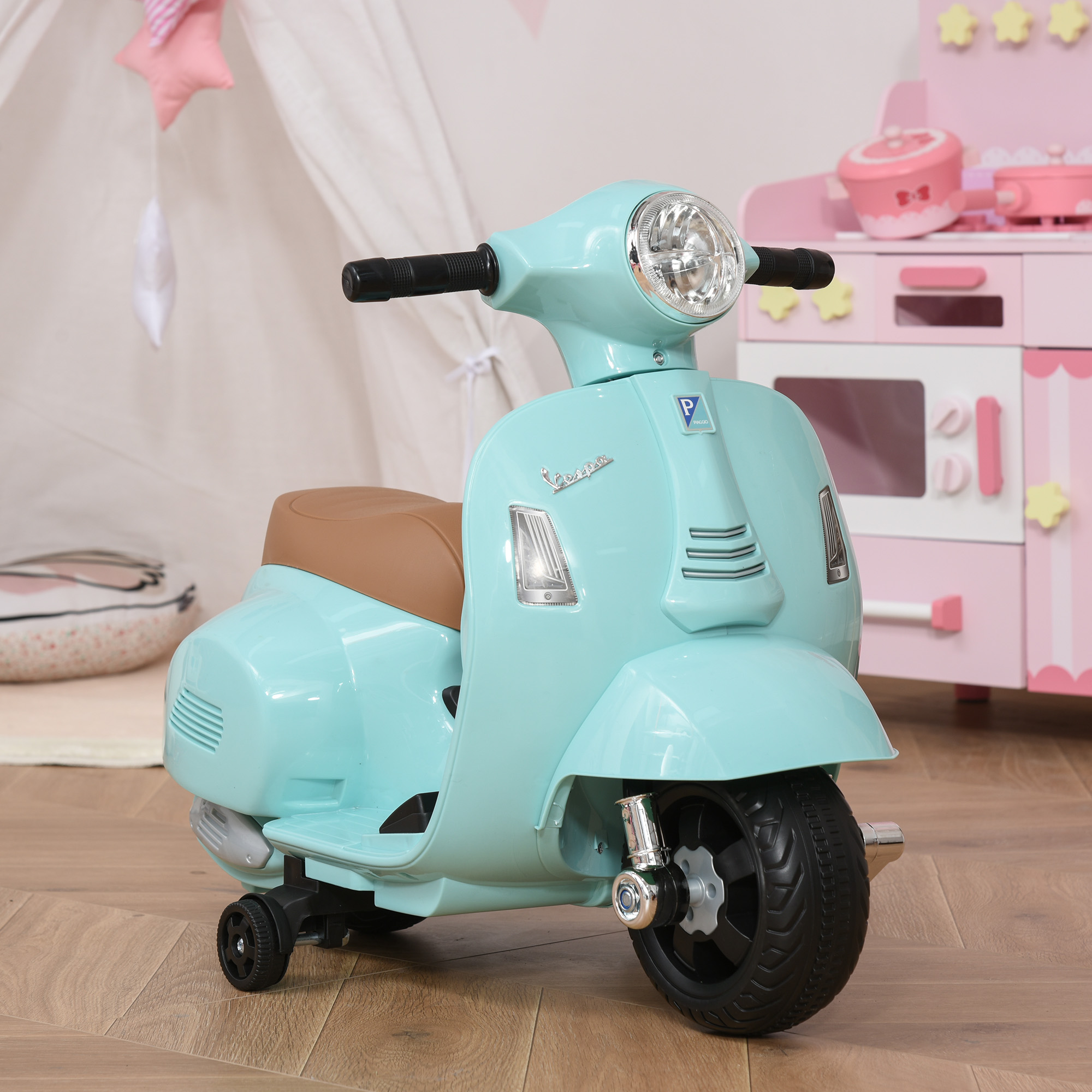 Un monopattino giocattolo azzurro con un sedile marrone, parcheggiato su un pavimento di legno. Un set di giocattoli rosa è sullo sfondo.