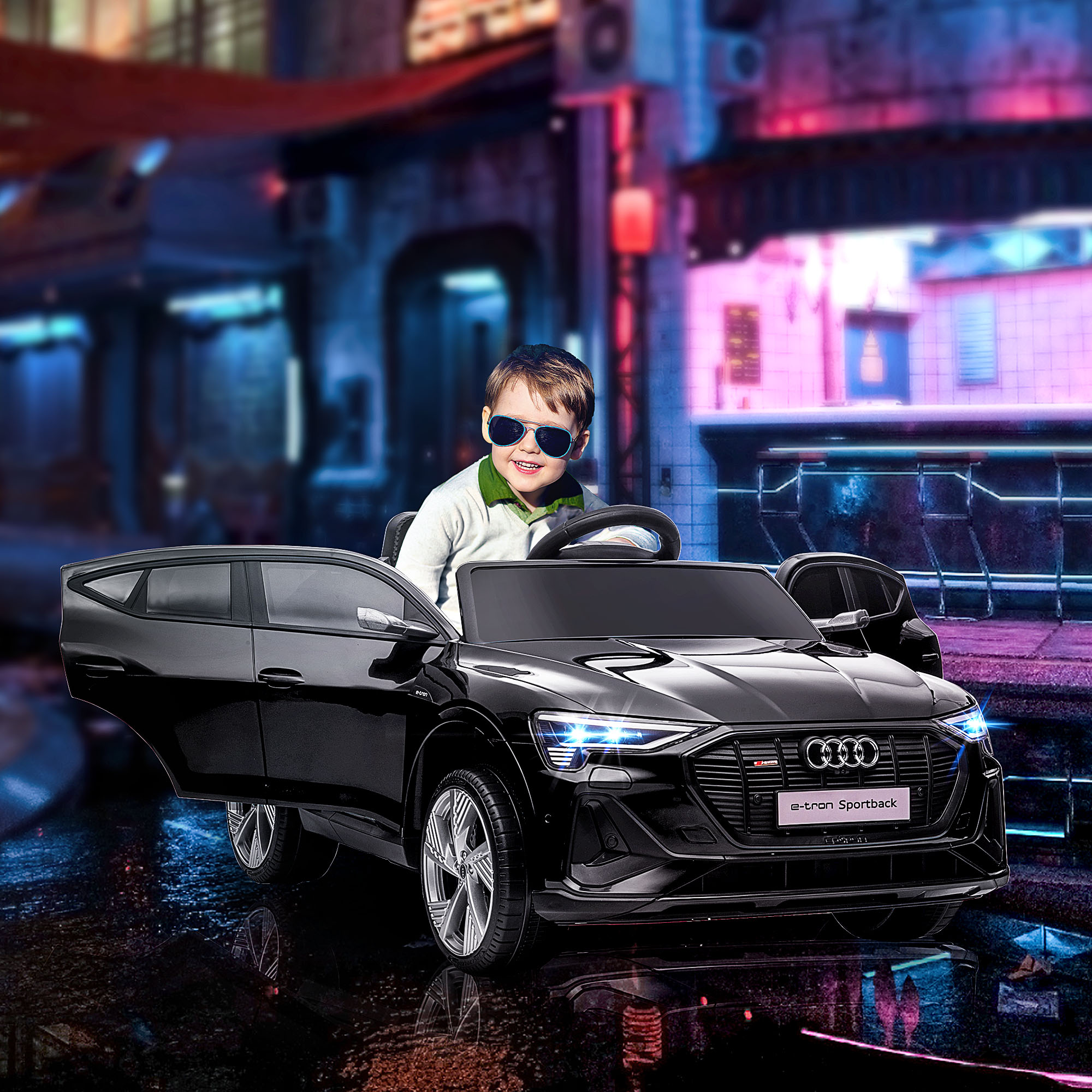 Un bambino con occhiali da sole in un'auto giocattolo nera con porte aperte, sfondo urbano.