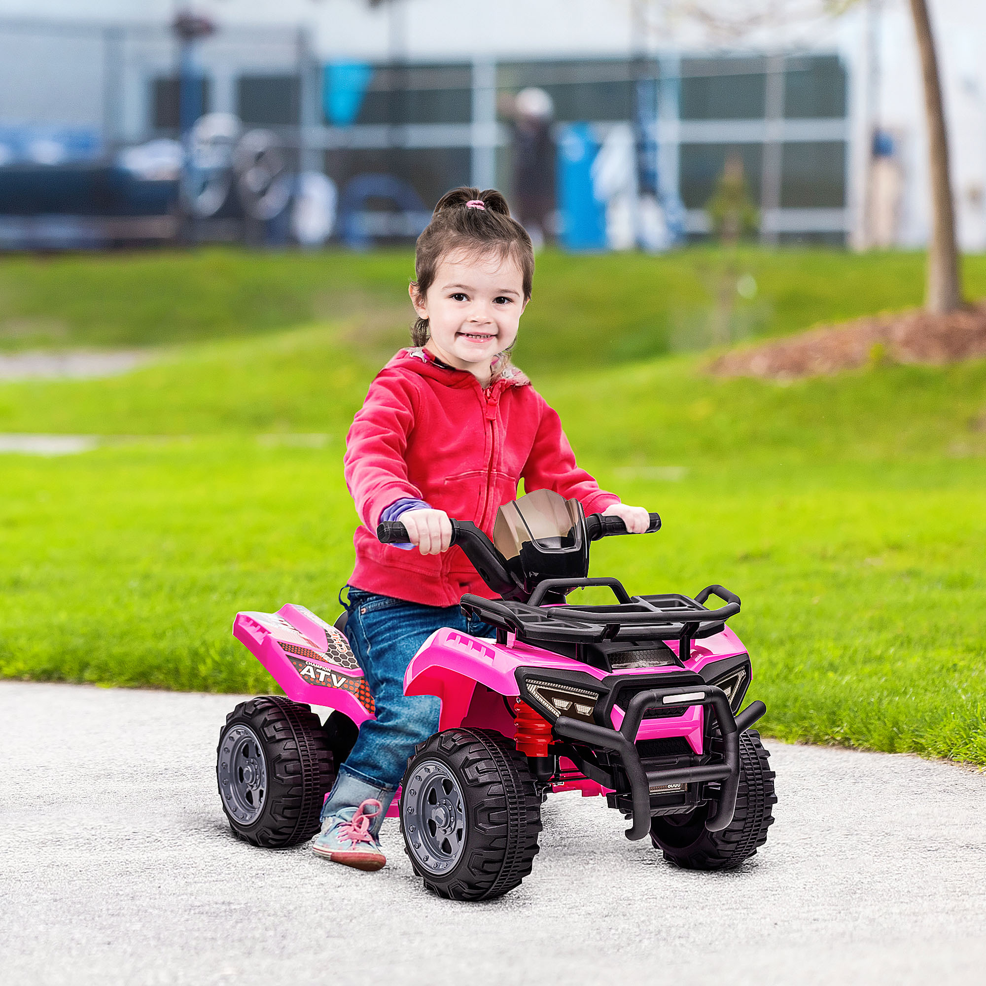 Ragazza su un ATV rosa, sorridente, su un sentiero pavimentato vicino all'erba verde.
