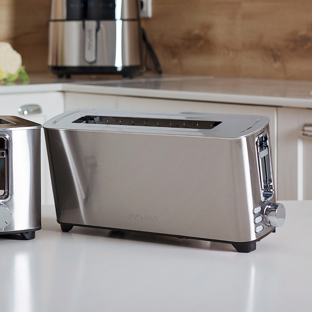 Ein silberner Toaster auf einer weißen Oberfläche. Ein weiterer Toaster ist links teilweise sichtbar.