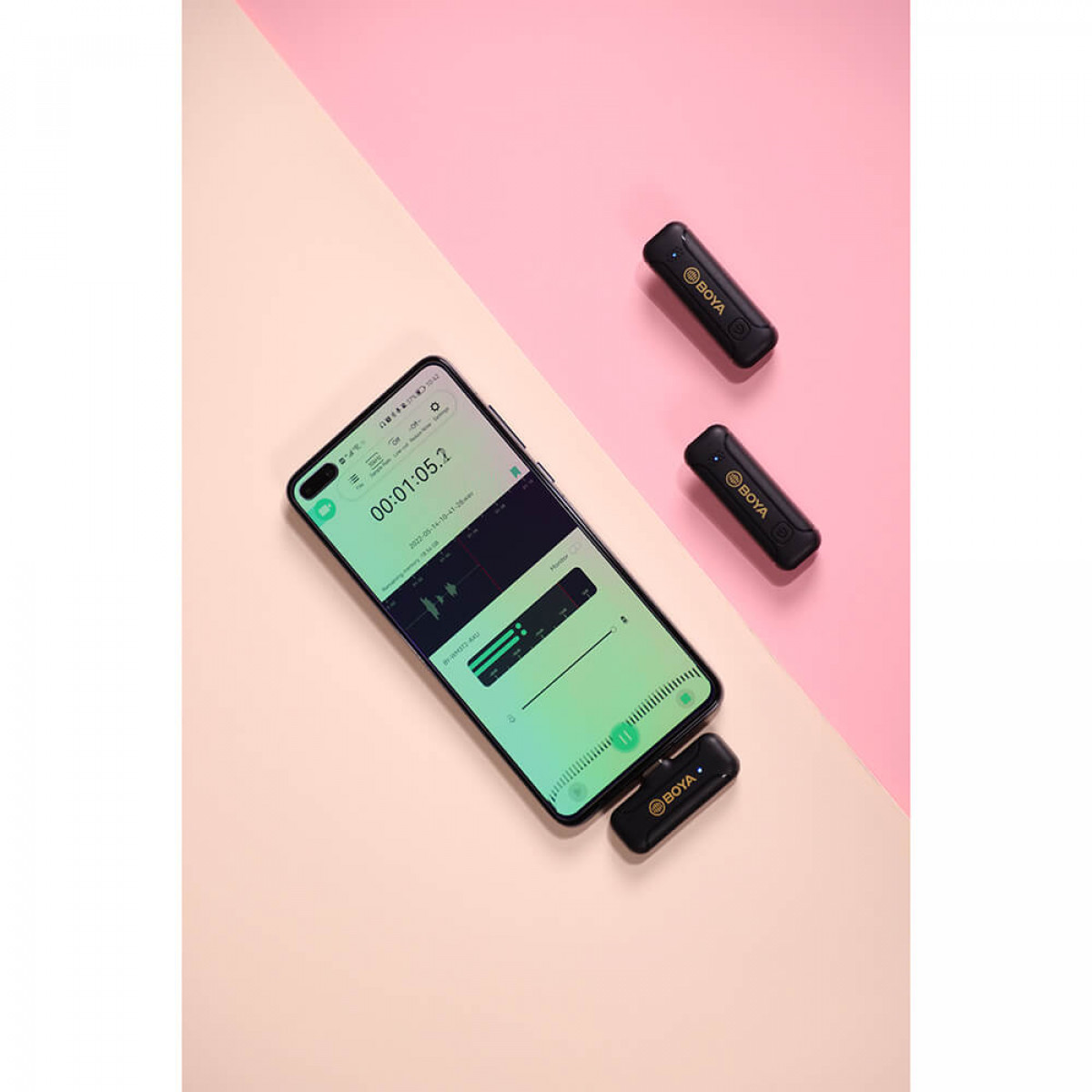 Smartphone met opname-interface en twee draadloze microfoons, roze achtergrond.