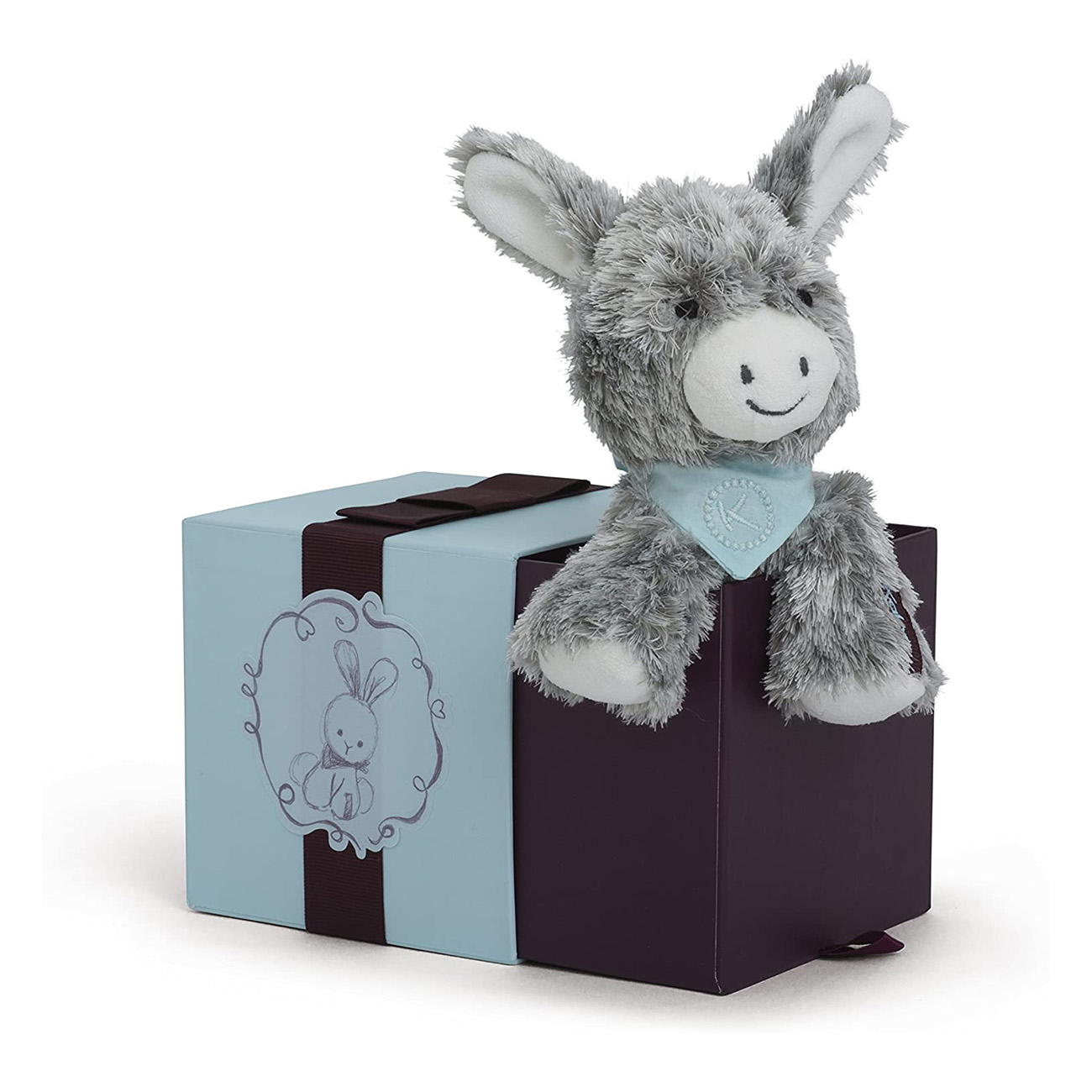 Szara pluszowa zabawka osła siedząca na pudełku. Pudełko jest w połowie jasnoniebieskie, w połowie fioletowe.