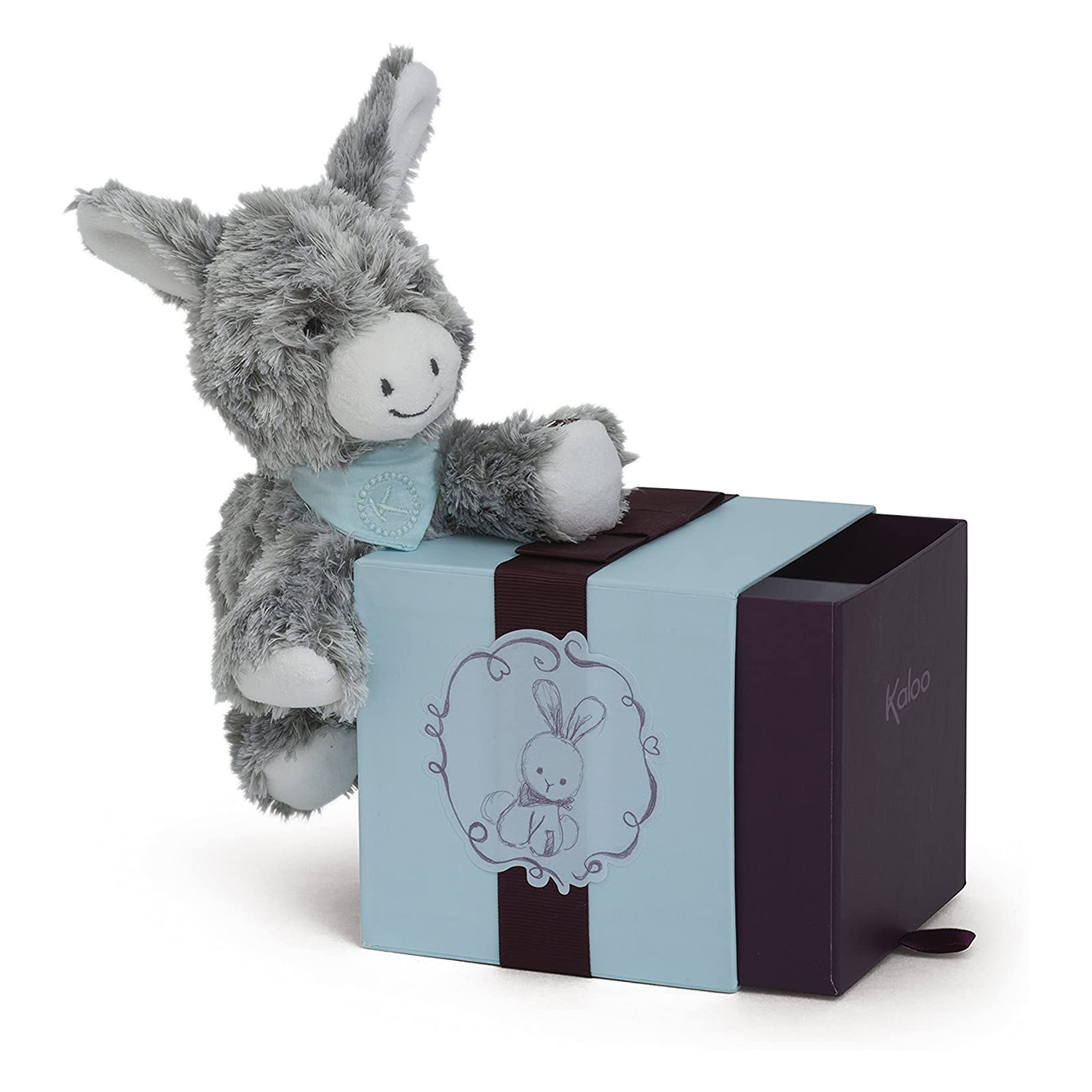 Szara pluszowa zabawka osła oparta na niebieskim pudełku z prezentem z wizerunkiem królika.