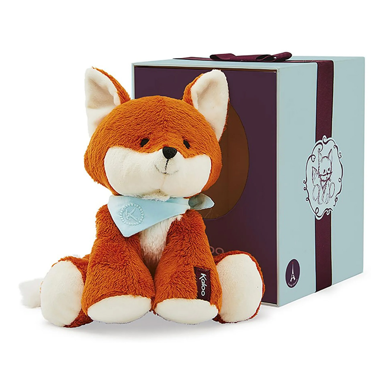 Une peluche de renard devant une boîte cadeau avec un ruban bleu. Le jouet a une écharpe bleue.