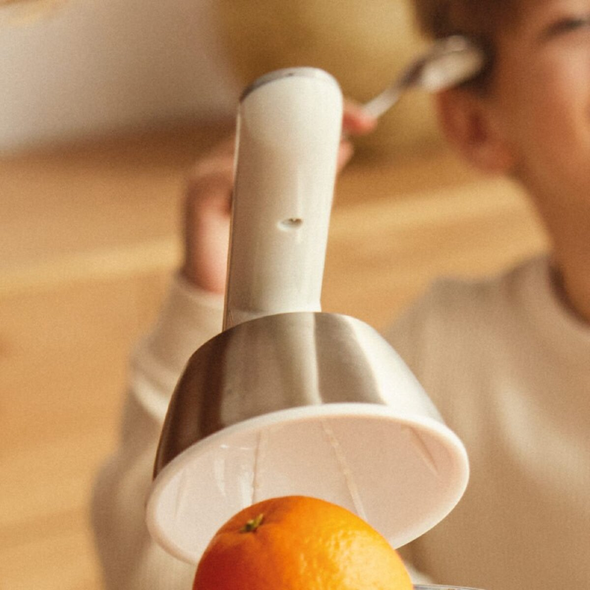 Una persona usando una herramienta de cocina para pelar una naranja sobre un fregadero.