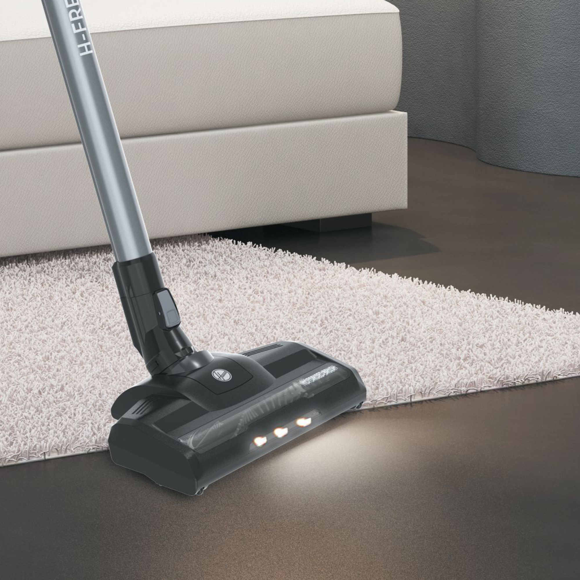 Staubsaugerkopf auf einem Teppich, mit eingeschalteten Lichtern. Grau und schwarz mit silberner Stange.