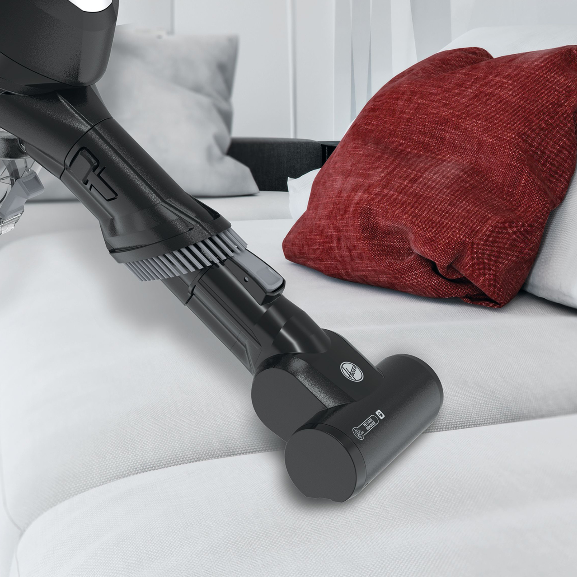 Staubsaugerkopf auf einem grauen Sofa. Der Staubsauger ist schwarz und hat einen Bürstenaufsatz.