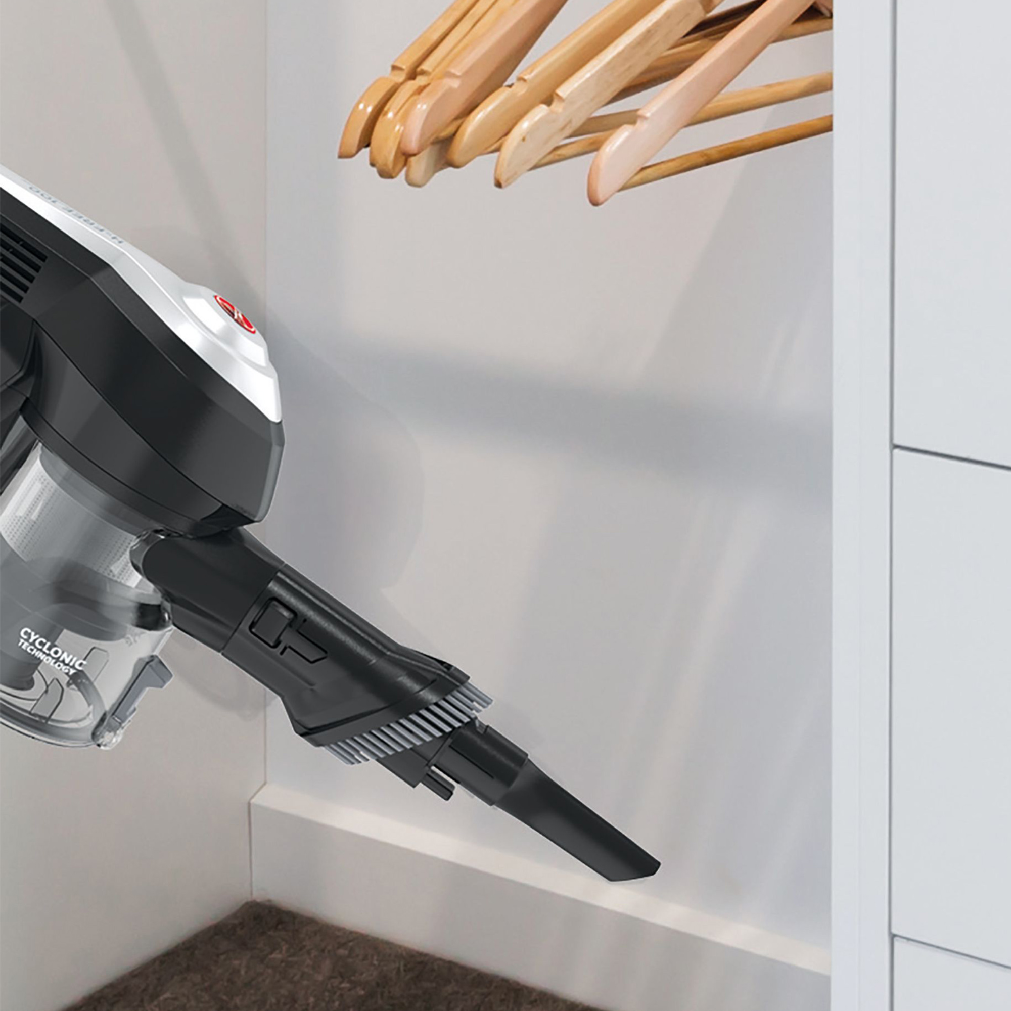 Handstaubsauger reinigt einen Schrank. Holzbügel sind im Hintergrund zu sehen.