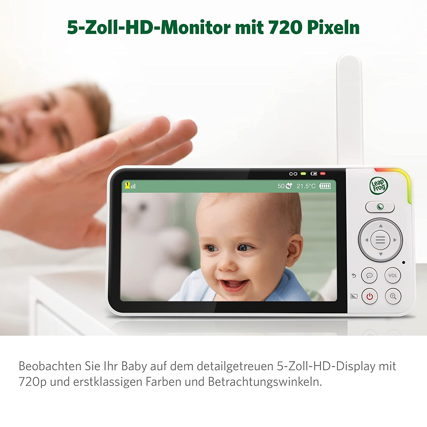 Babyphone, das ein lächelndes Baby auf einer weißen Oberfläche zeigt, mit der Hand einer Person im Hintergrund.