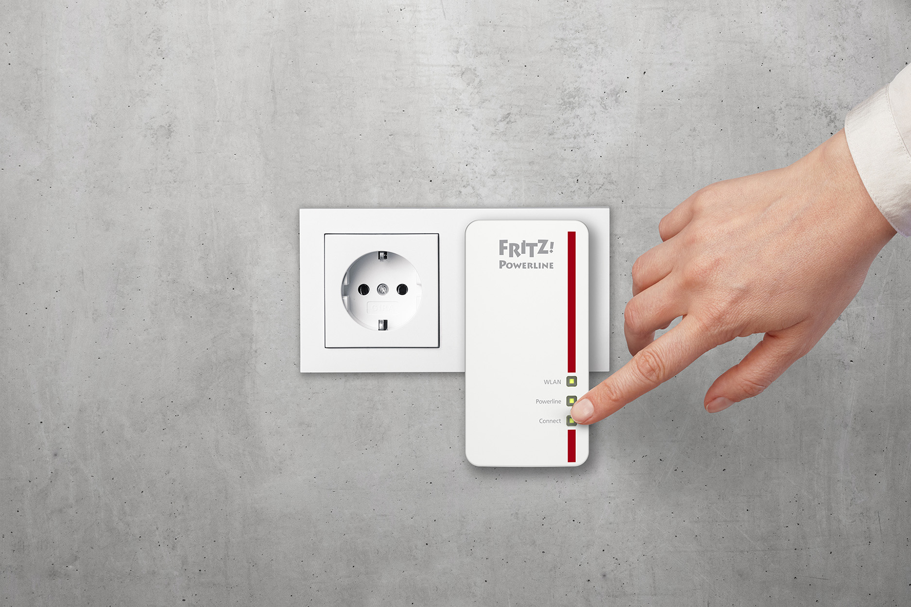 Una mano tocca un adattatore powerline bianco e rosso collegato a una presa a muro grigia.