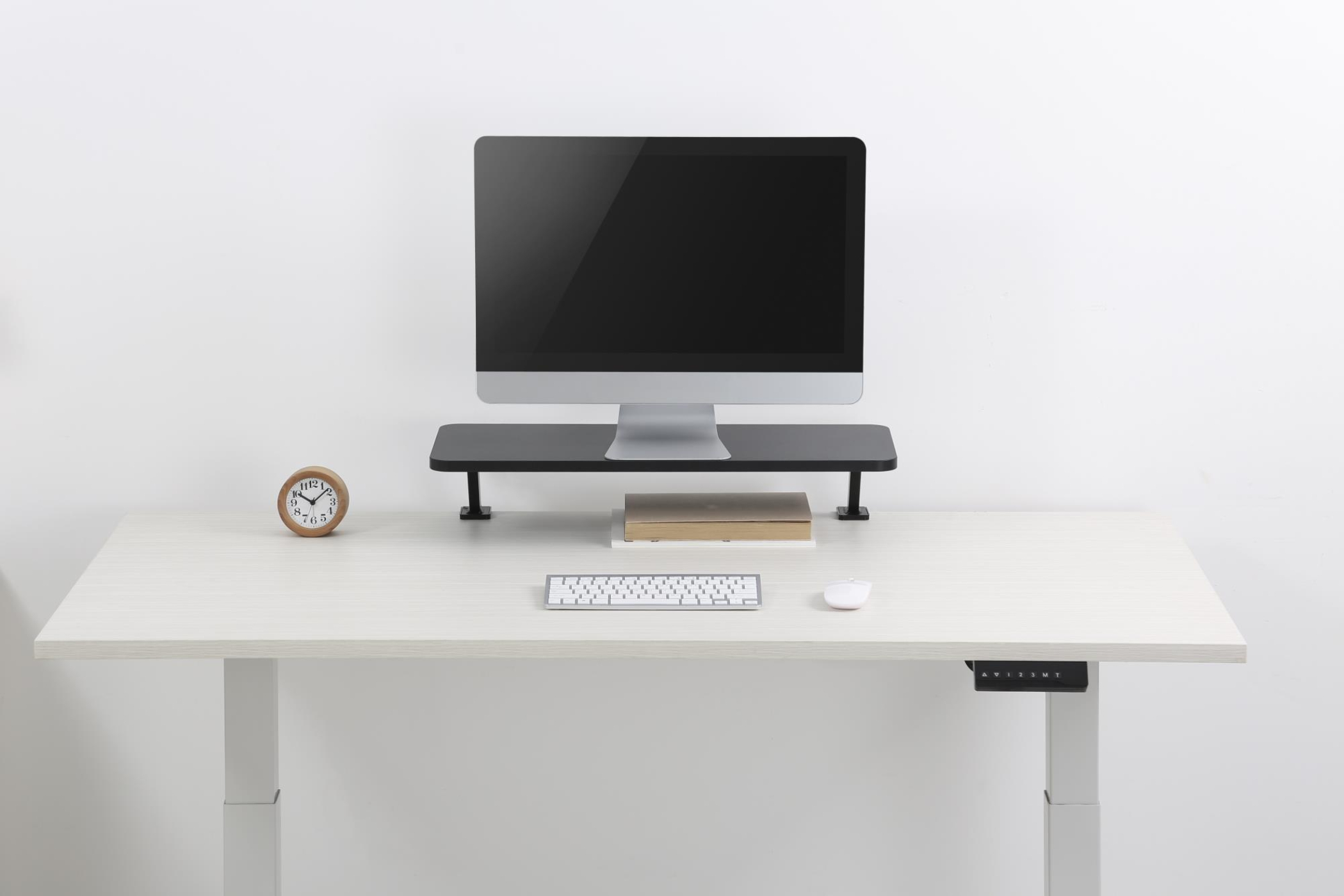 Schreibtisch mit Monitor, Ständer, Tastatur, Maus und Uhr.