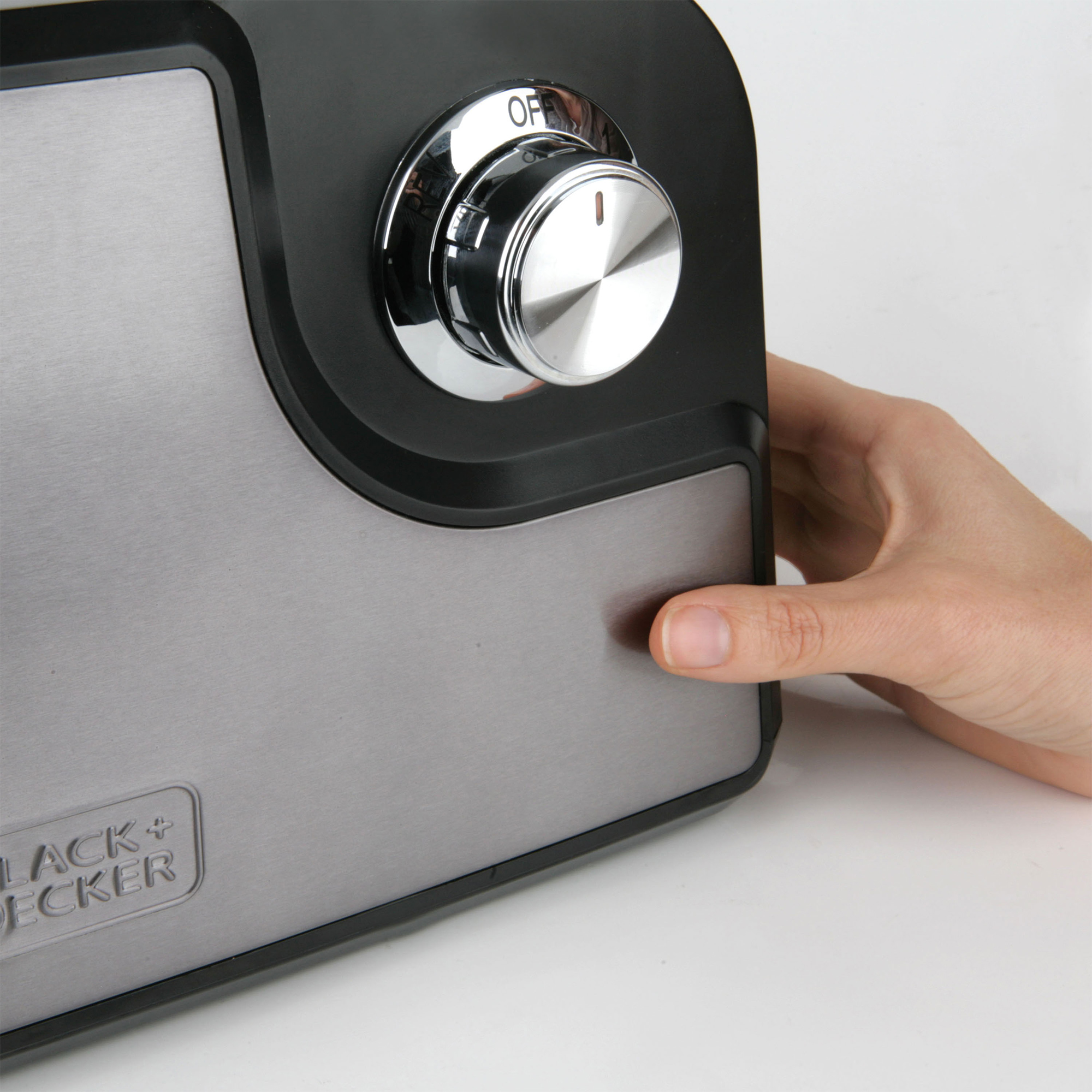 Dłoń obracająca chromowane pokrętło na czarno-srebrnym urządzeniu.