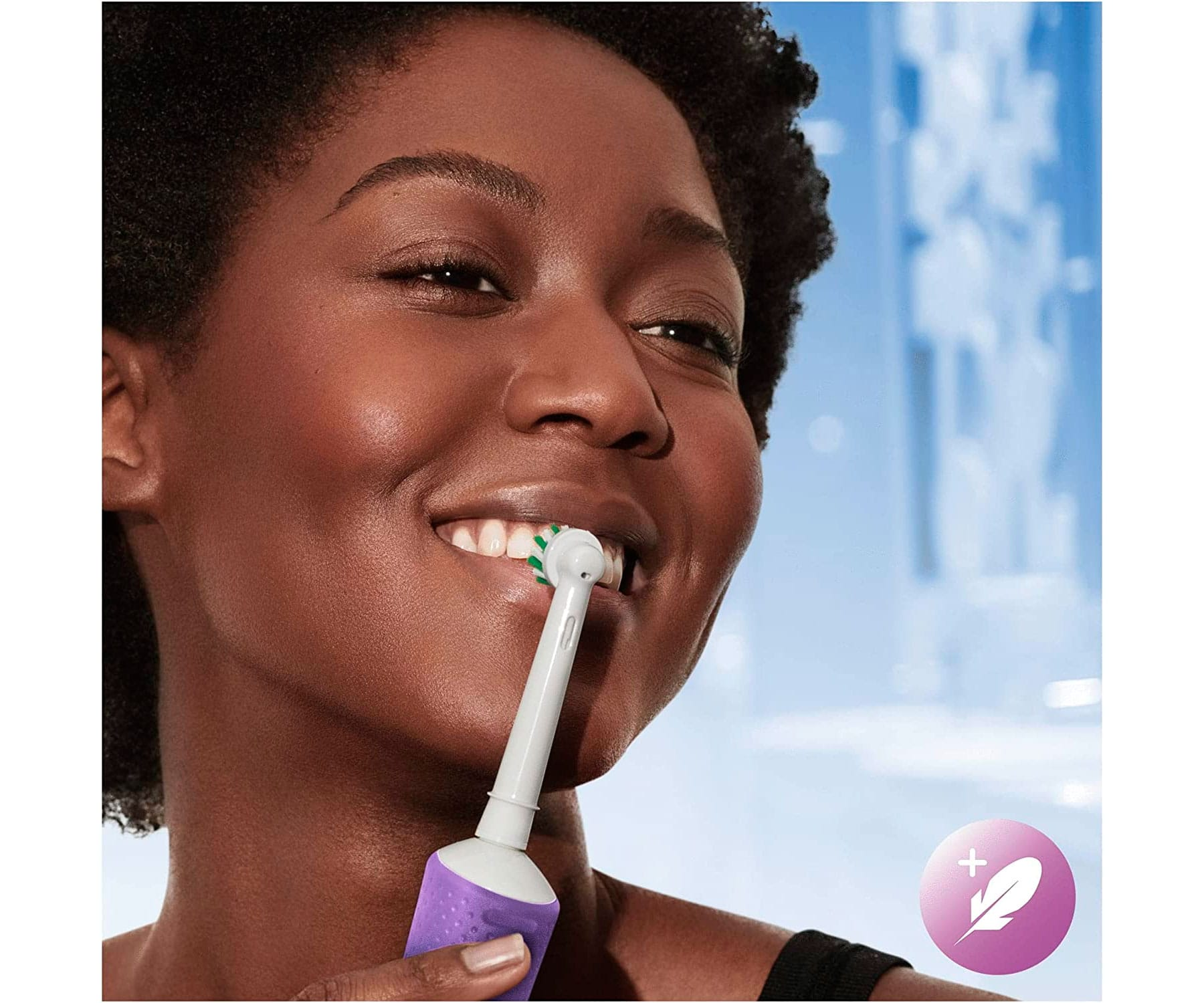 Kobieta myje zęby szczoteczką elektryczną. Zbliżenie, uśmiechnięta. Fioletowy uchwyt.