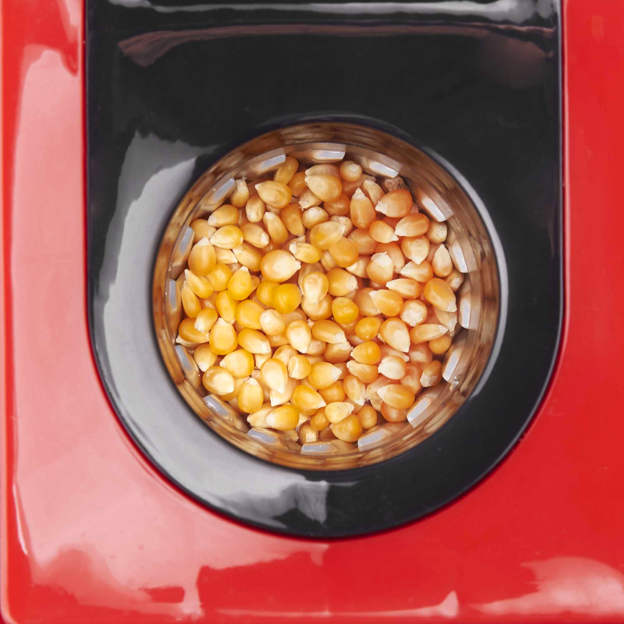 Vista superior de una máquina de palomitas roja con granos dentro.