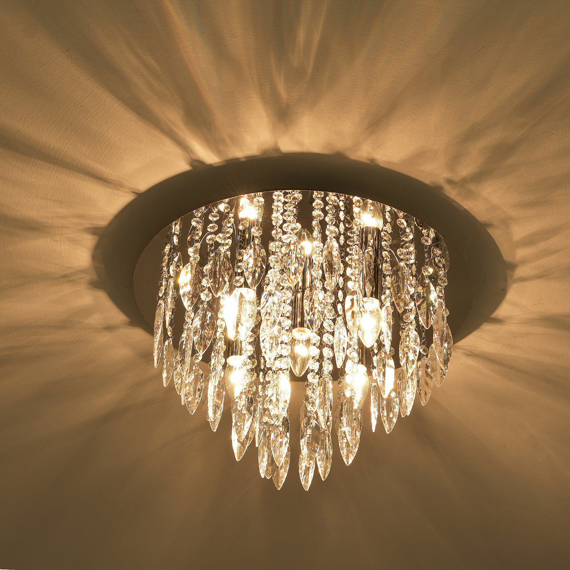 Kronleuchter, Kristalle, Licht. Schatten an der Decke. Klare Kristalle, silberner Rahmen.