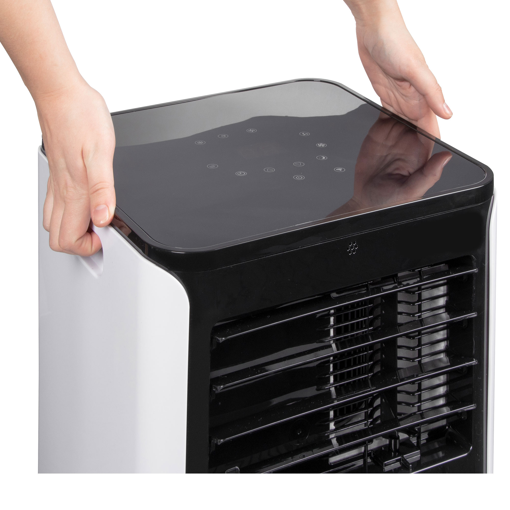 Ręce trzymają biało-czarną chłodziarkę powietrza. Ma górny panel z przyciskami sterowania.