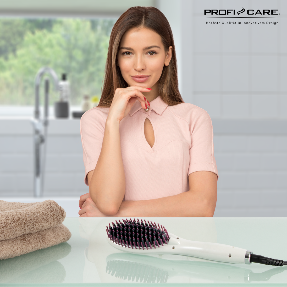 Kobieta w różowej bluzce, trzymająca podbródek, prostownica do włosów i ręczniki na stole.