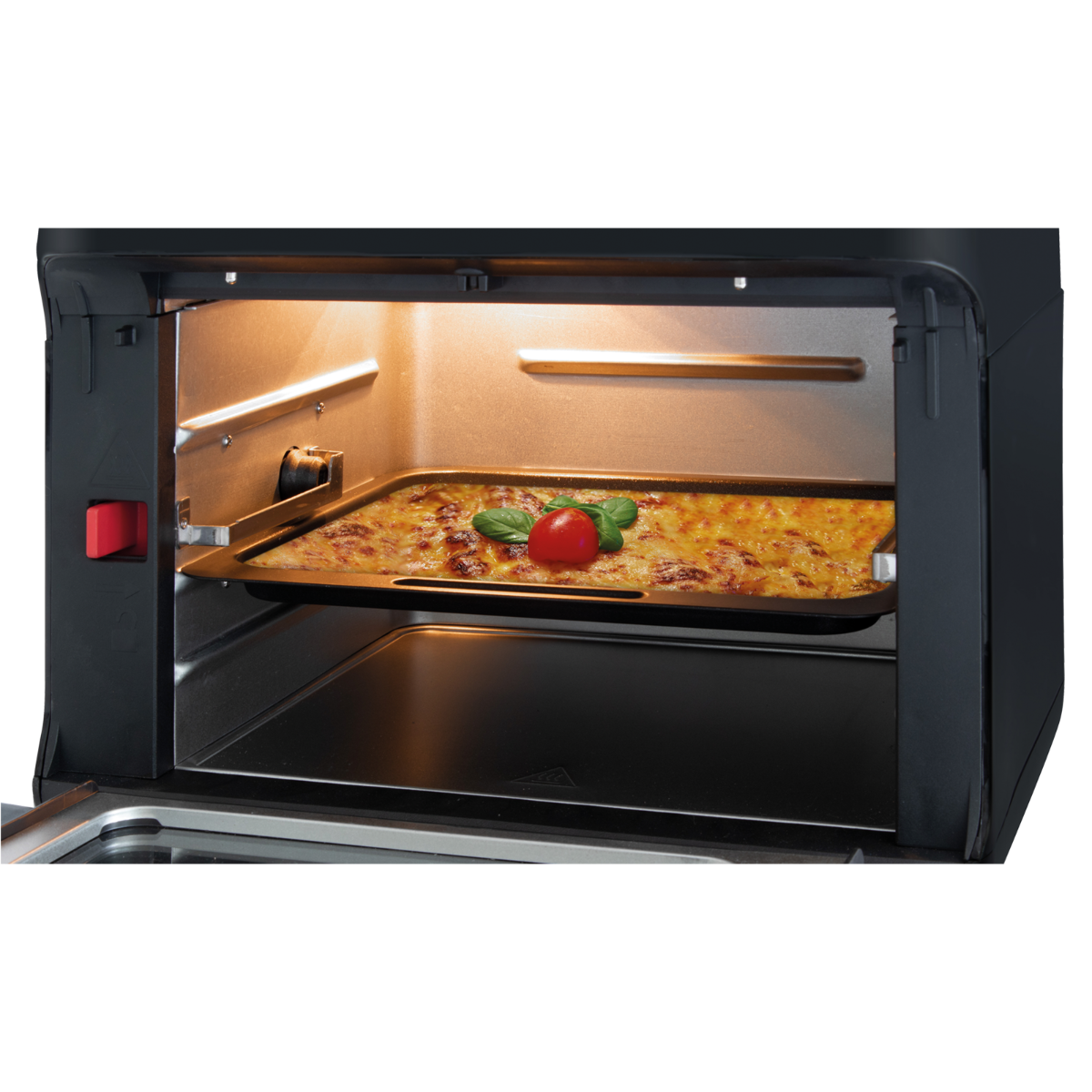 Wnętrze piekarnika z tacą z jedzeniem i pomidorem, z otwartymi drzwiami.