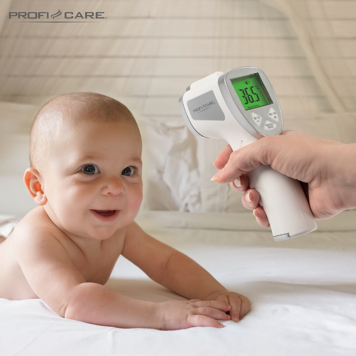 Ein Baby liegt auf einem weißen Laken, ein Thermometer wird in der Nähe gehalten. Das Thermometer zeigt 36,5.