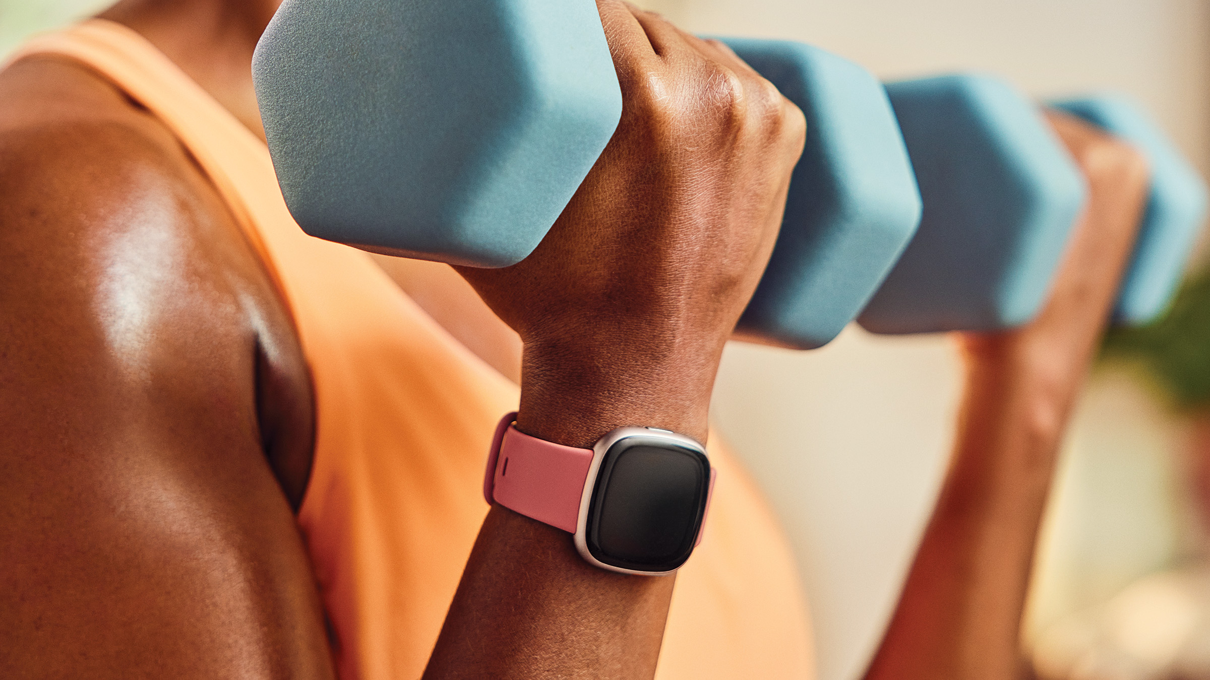 Osoba ćwicząca z hantlami, nosząc na nadgarstku smartwatch.