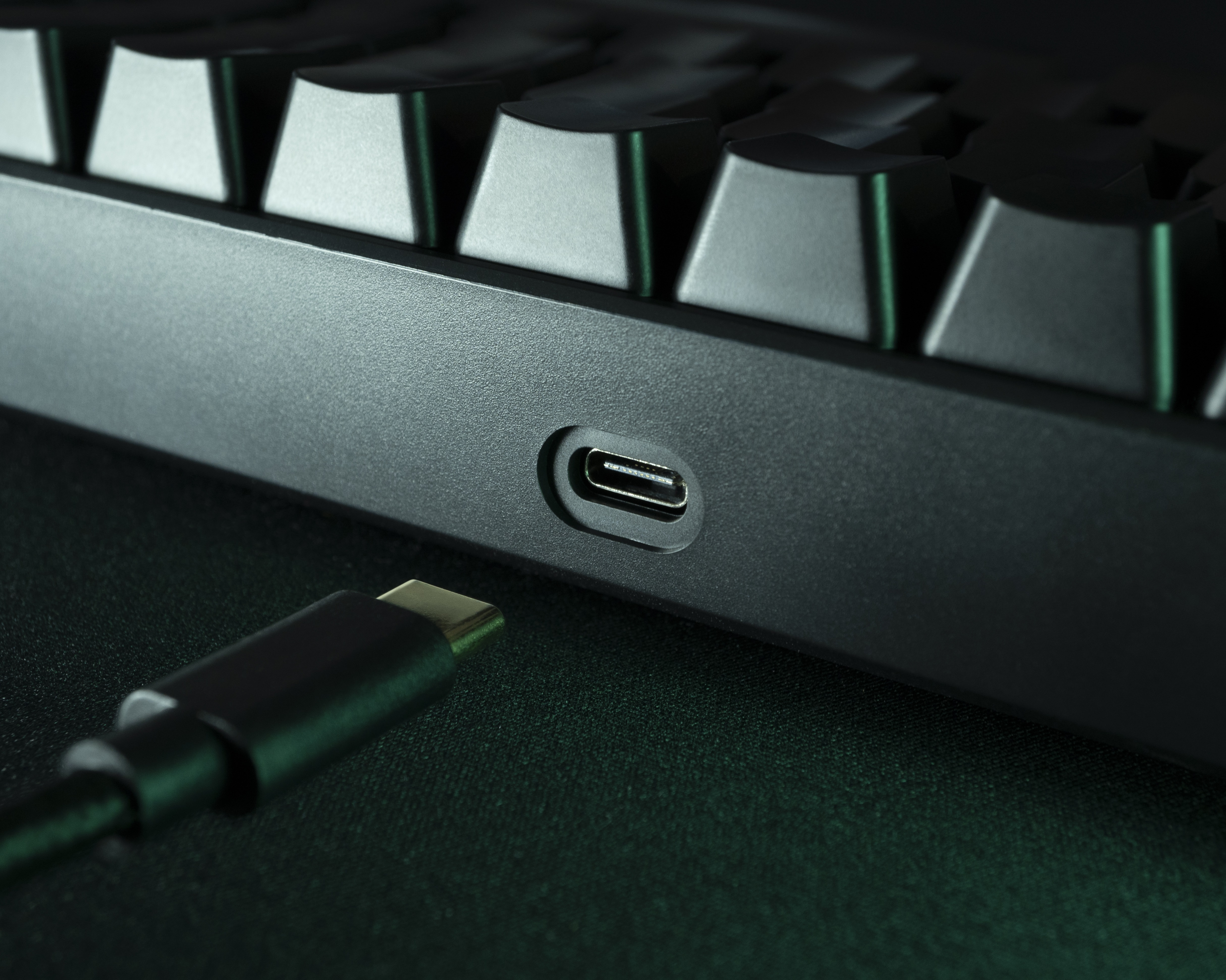 Nahaufnahme einer schwarzen Tastatur mit USB-C-Anschluss und angeschlossenem Kabel.
