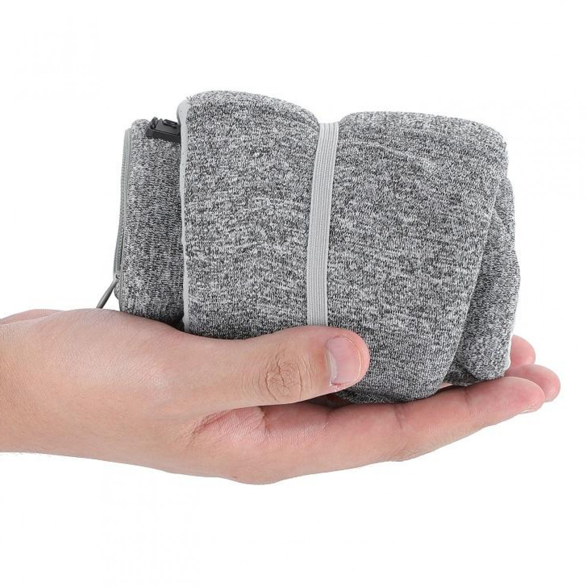 Une main tenant un petit objet gris plié avec un compartiment zippé et un élastique.