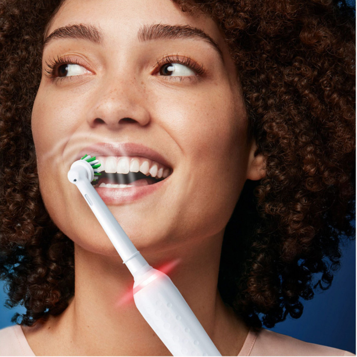 Donna che si lava i denti con uno spazzolino elettrico, mostrando denti e gengive.