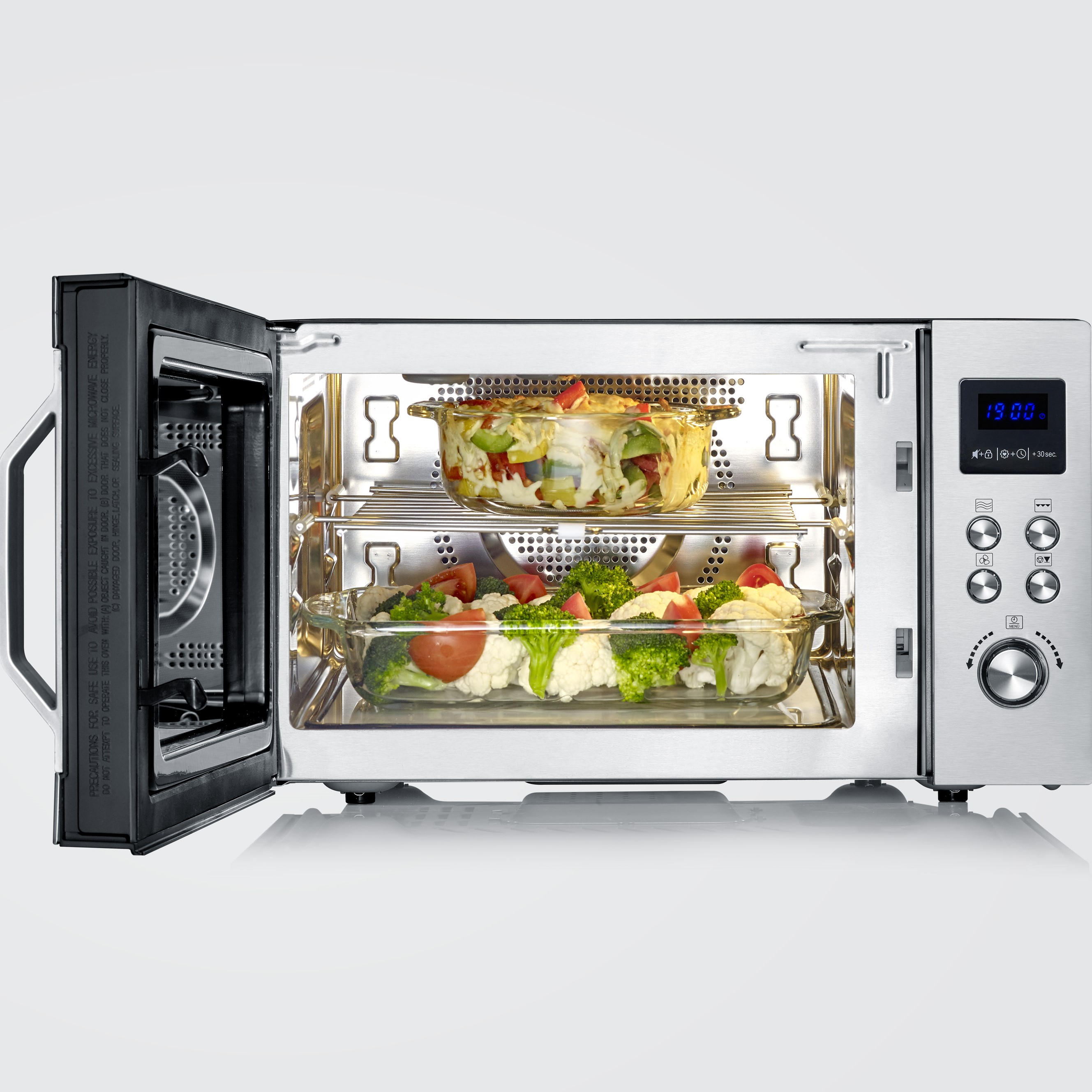 Piekarnik mikrofalowy z otwartymi drzwiami, zawierający jedzenie w szklanych naczyniach.