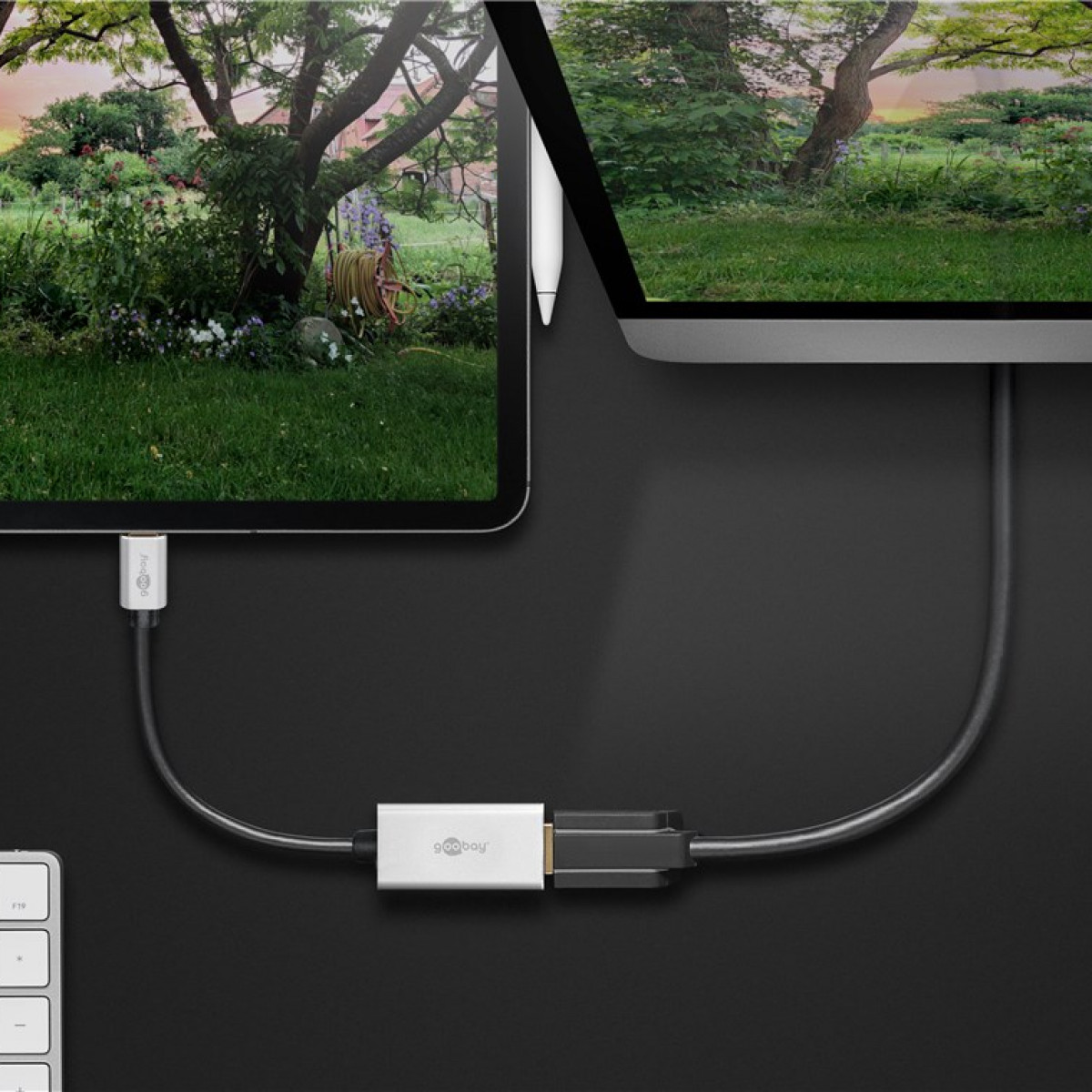 Tablets mit Kabel und Adapter verbunden. Grüner Hintergrund. Naturszene auf dem Tablet-Bildschirm.