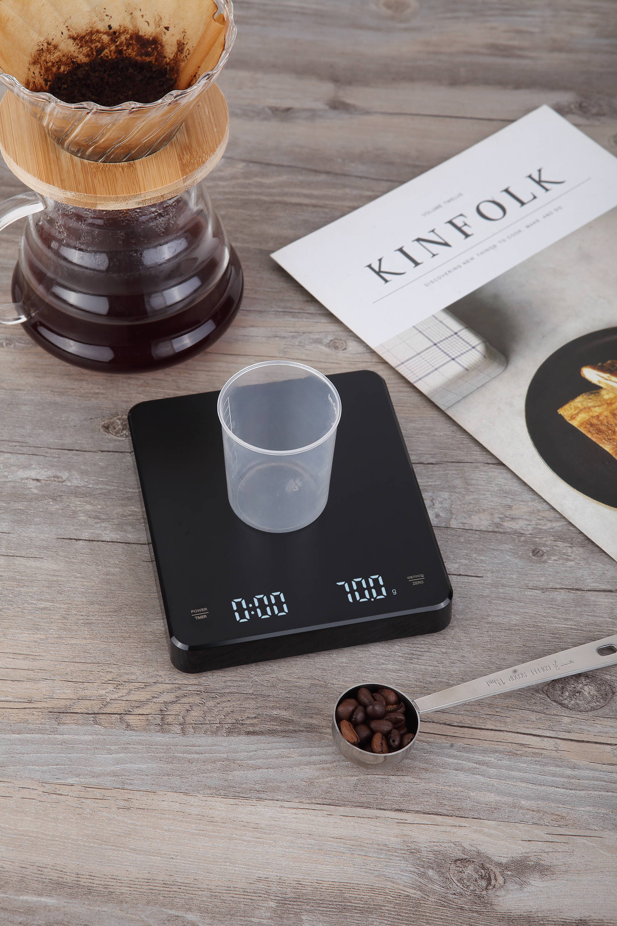 Waga do kawy z filiżanką, zmieloną kawą i łyżką. Magazyn Kinfolk obok.